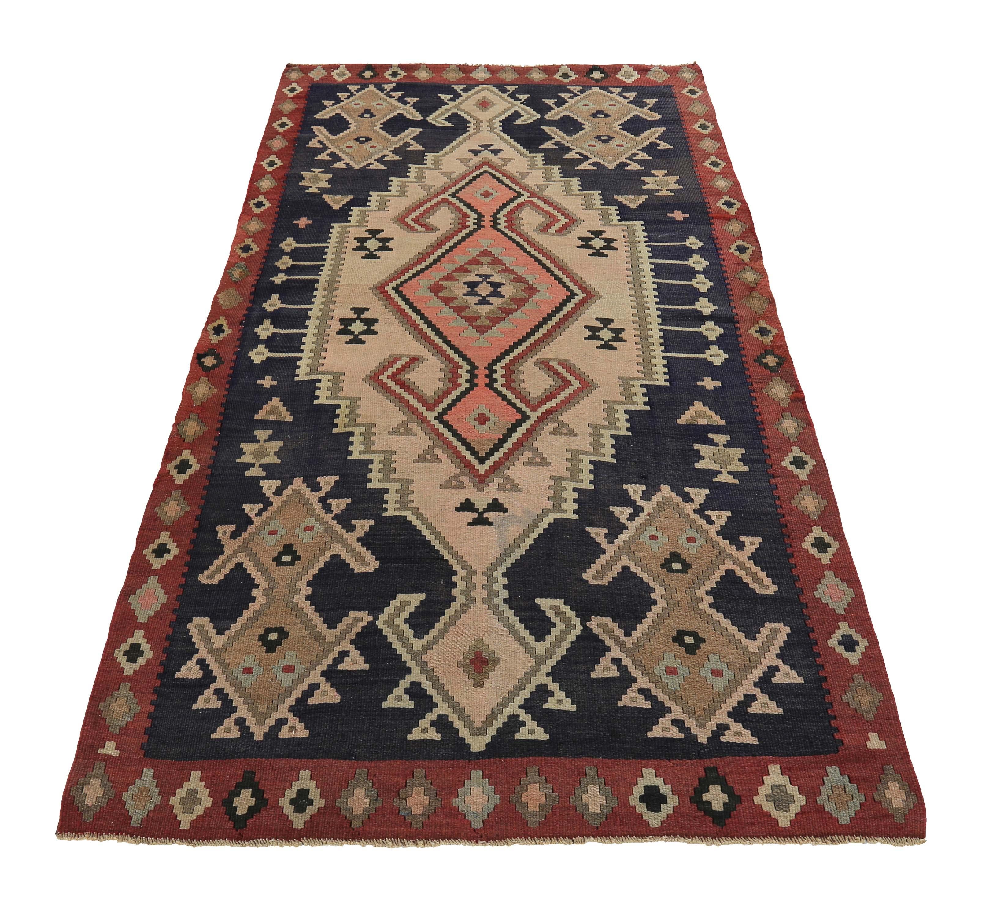 Turkish rug handwoven from the finest sheep’s wool and colored with all-natural vegetable dyes that are safe for humans and pets. It’s a traditional Kilim flat-weave design featuring orange, beige and brown tribal diamond patterns on a black field.