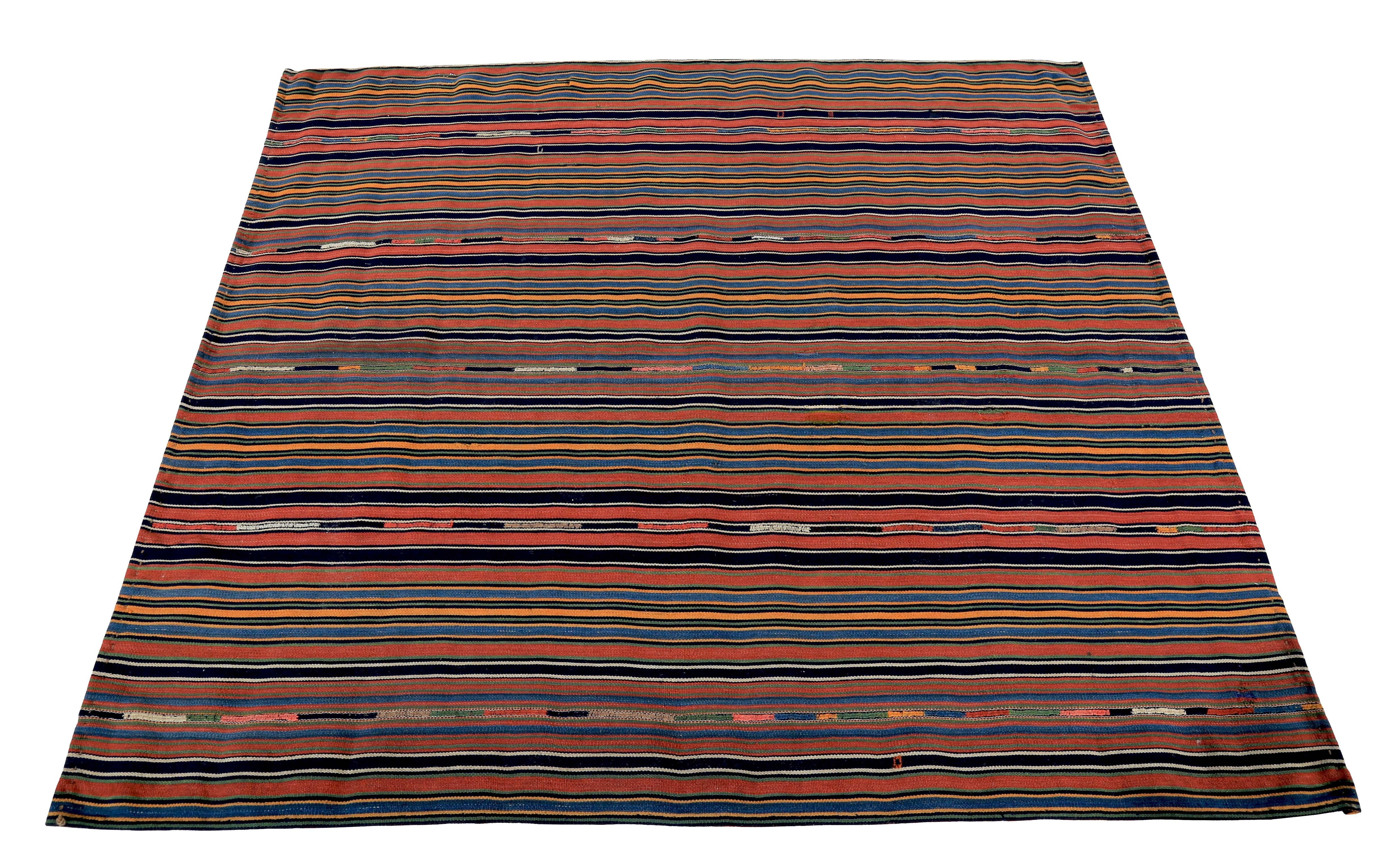 Modern Turkish rug handwoven from the finest sheep’s wool and colored with all-natural vegetable dyes that are safe for humans and pets. It’s a traditional Kilim flat-weave design featuring a red field with orange, black and blue pencil stripes.