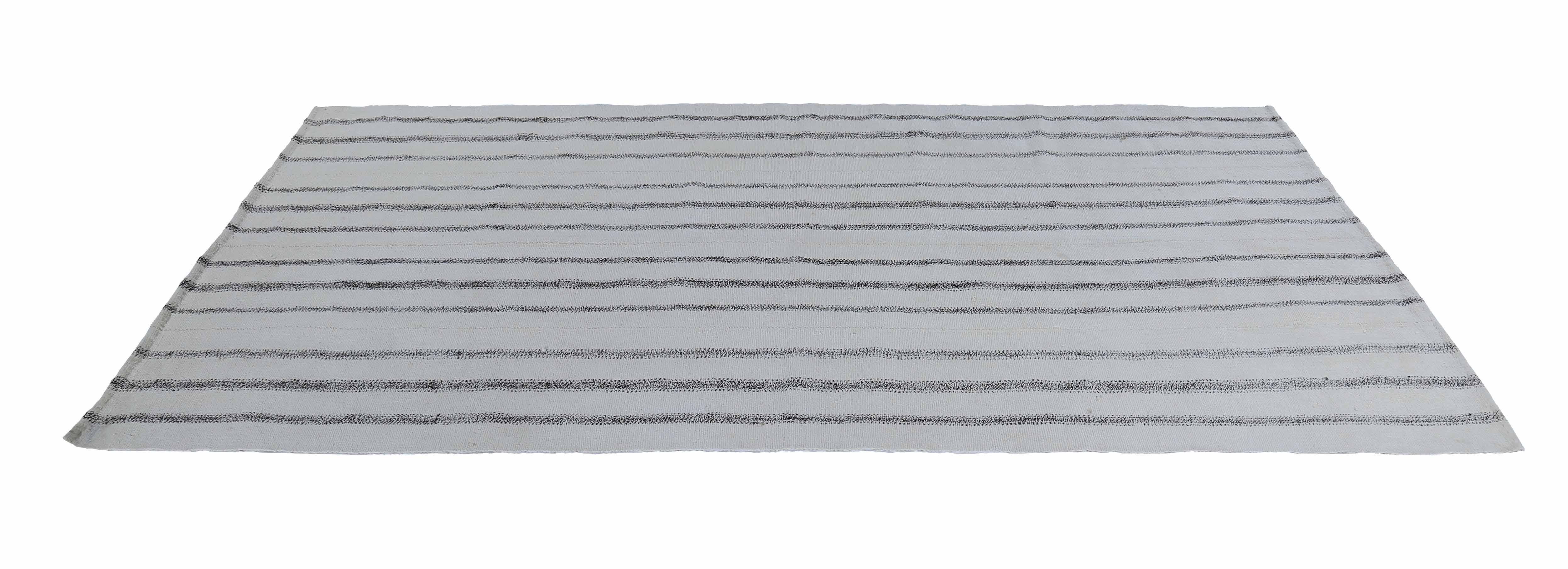 Modern Turkish rug handwoven from the finest sheep’s wool and colored with all-natural vegetable dyes that are safe for humans and pets. It’s a traditional Kilim flat-weave design featuring a white field with black pencil stripes. It’s a stunning