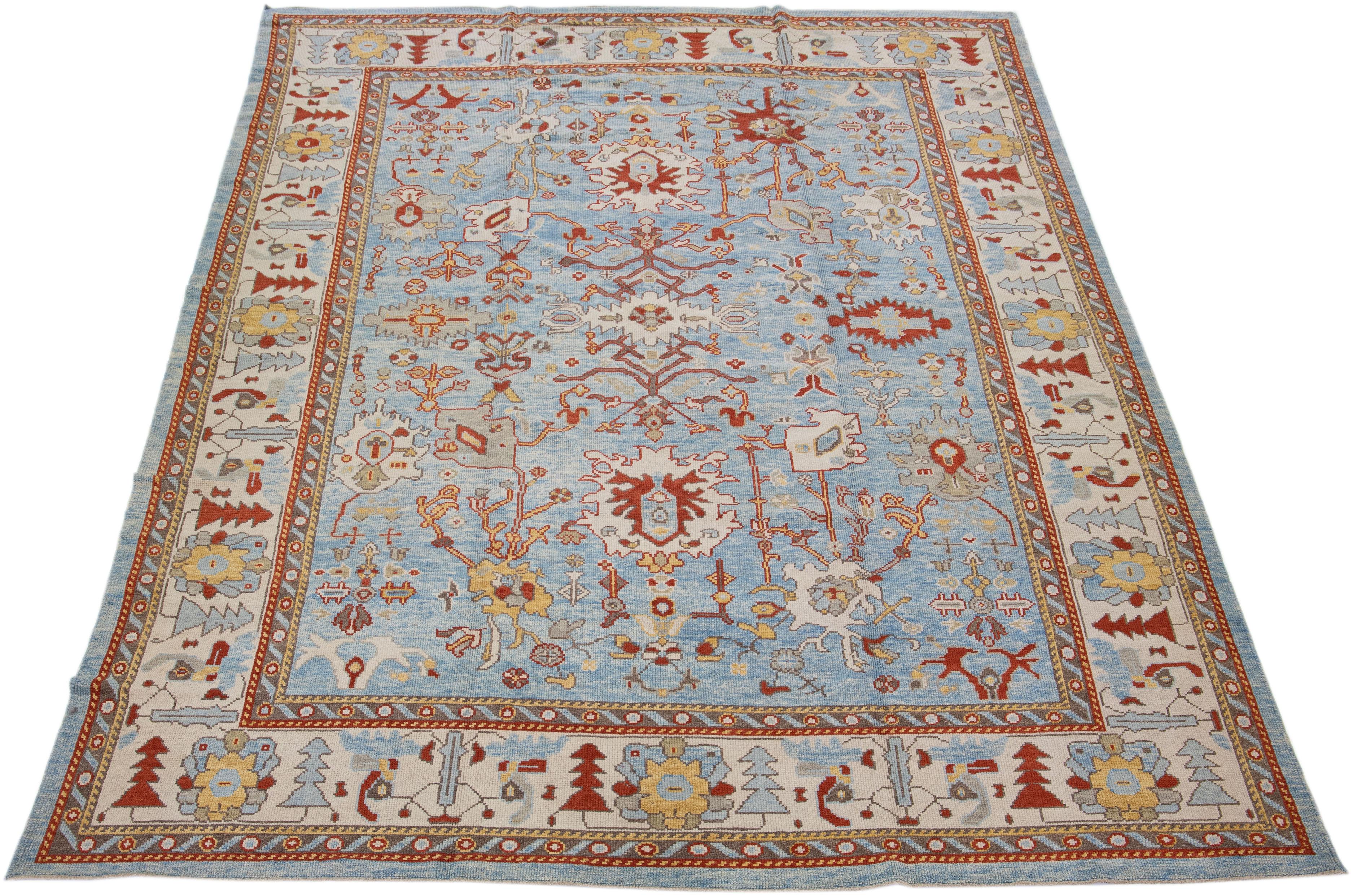 Beautiful modern Oushak hand-knotted wool rug with a blue color field. This Turkish Piece has a beige frame with rust, yellow, and gray accent colors in a gorgeous all-over floral design.

This rug measures: 9'2
