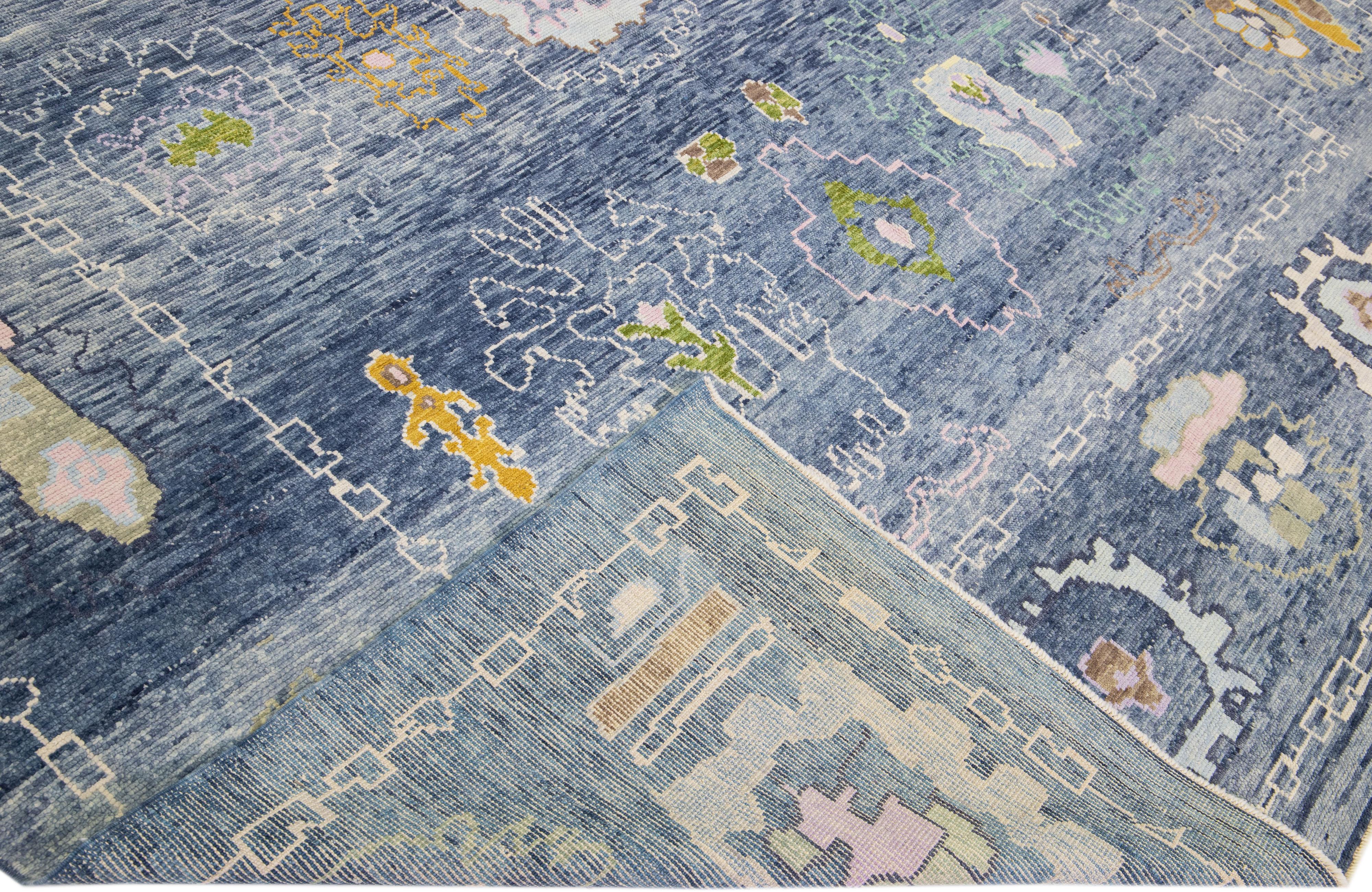 Beautiful modern Oushak hand-knotted wool rug with a blue color field. This Turkish Piece has yellow, orange, and green accent colors in a gorgeous all-over floral design.

This rug measures: 10' x 12'10