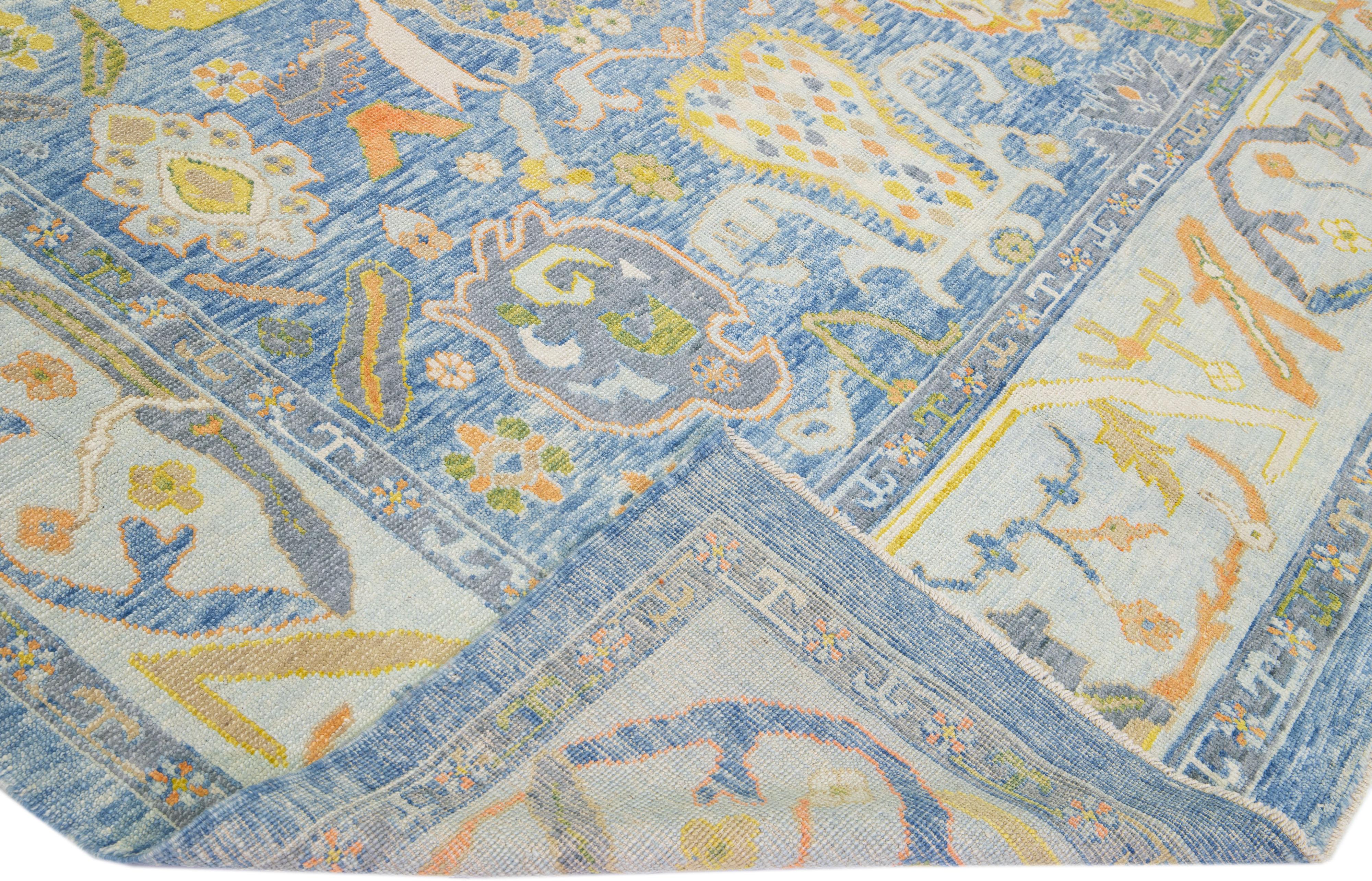 Beautiful modern Oushak hand-knotted wool rug with a blue color field. This Turkish Piece has yellow, orange, and green accent colors in a gorgeous all-over floral design.

This rug measures: 10'4