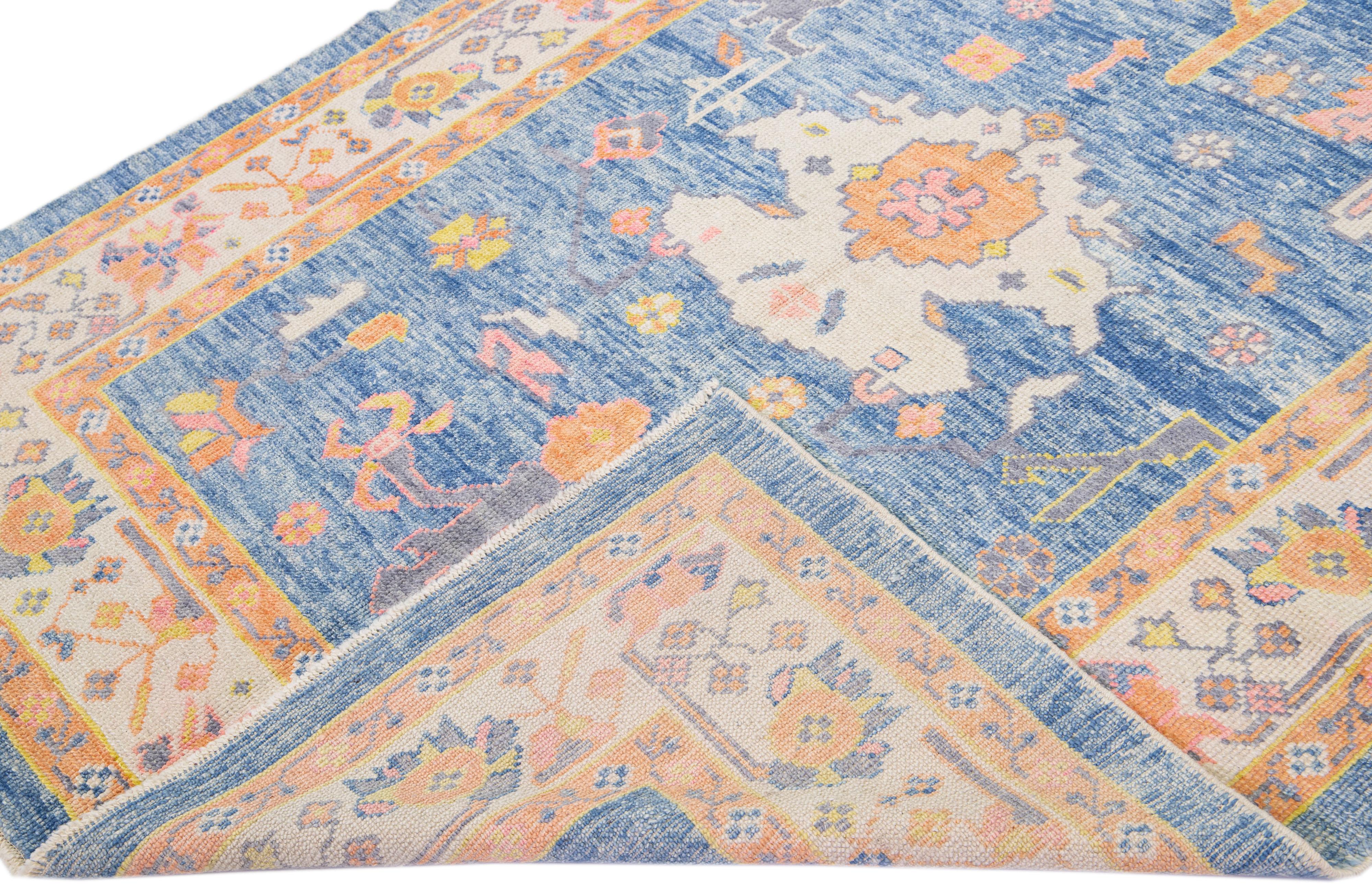 Beautiful modern Oushak hand-knotted wool rug with a navy blue color field. This Turkish Piece has a beige frame with yellow, orange, pink, and green accent colors in a gorgeous all-over floral design.

This rug measures: 5'9