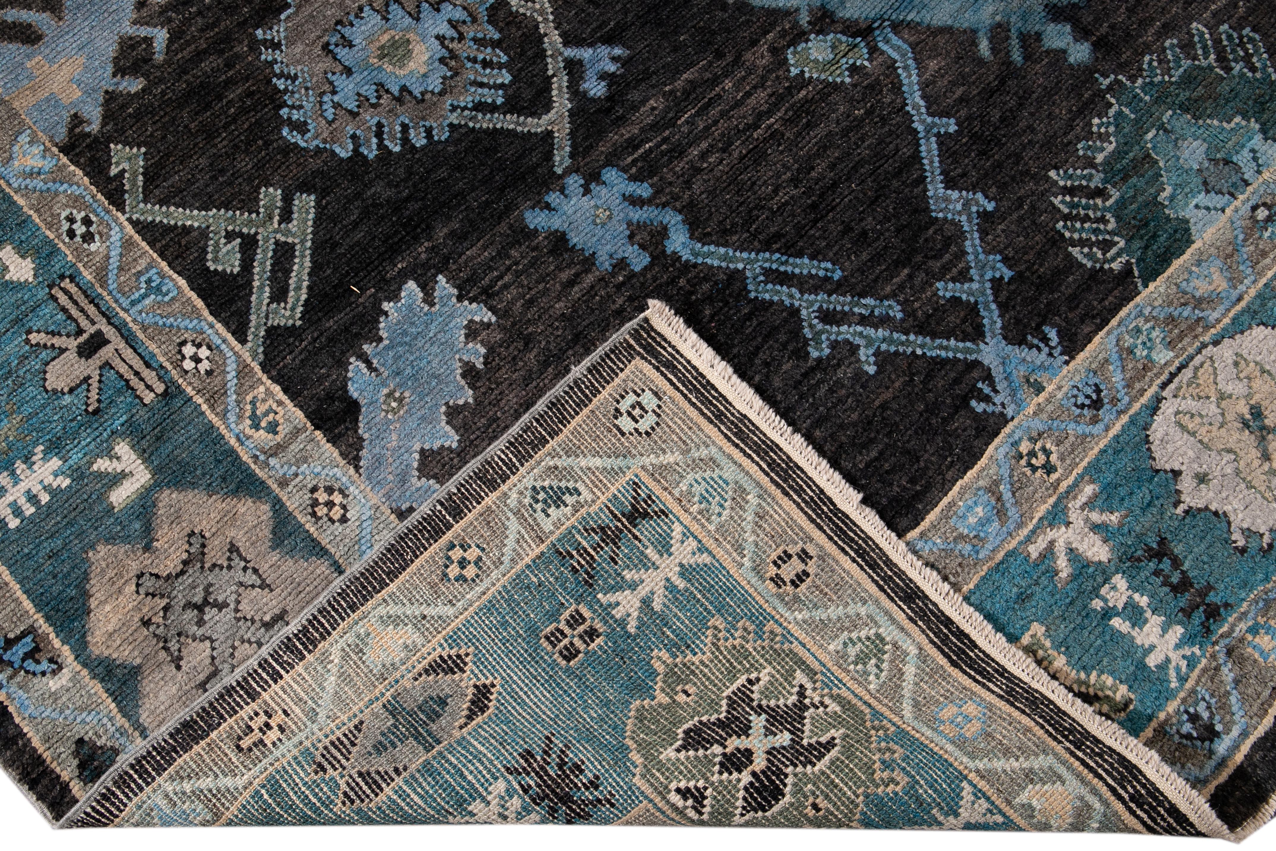 Beautiful modern Oushak hand knotted wool rug with a black field. This Oushak rug has a blue frame and accents of tan, green, and ivory all over a gorgeous geometric floral design.

This rug measures: 9'11