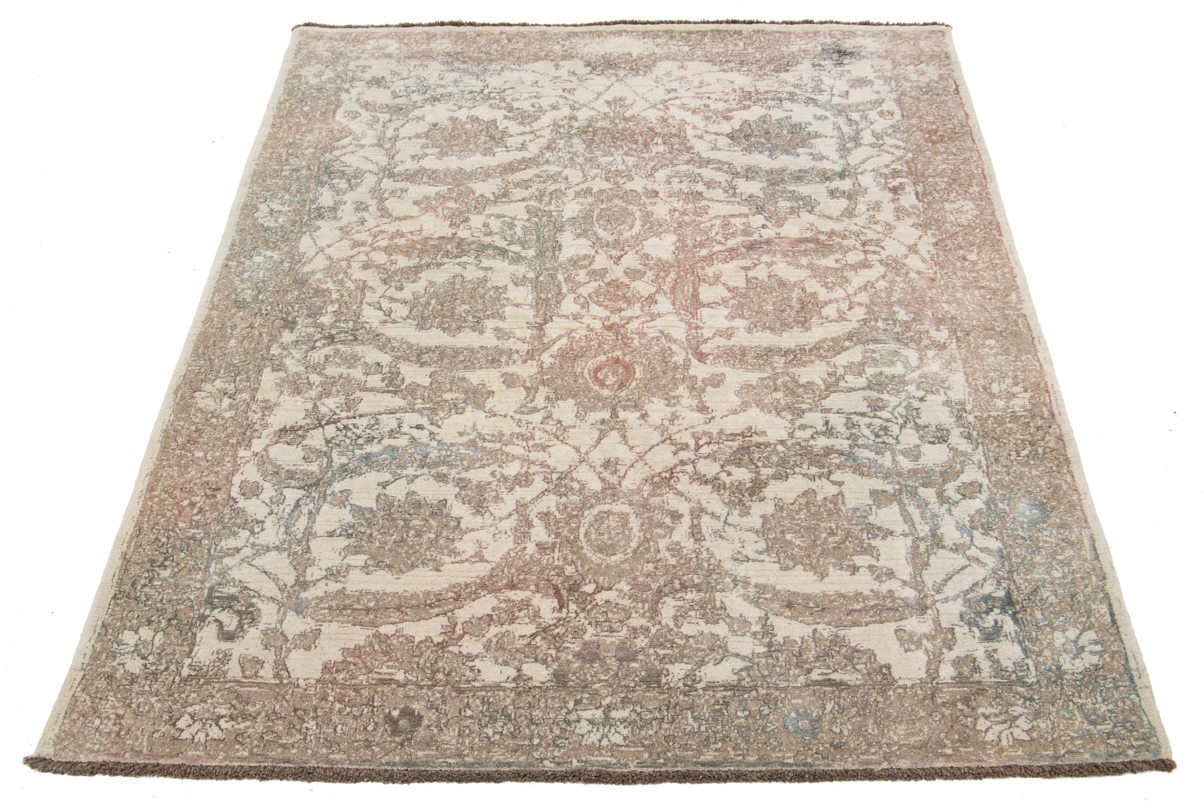 A beautiful modern Oushak rug made of hand-knotted wool. The rug features a beige field with brown, green, and peach accents in a stunning floral design.

This rug measures 5'7