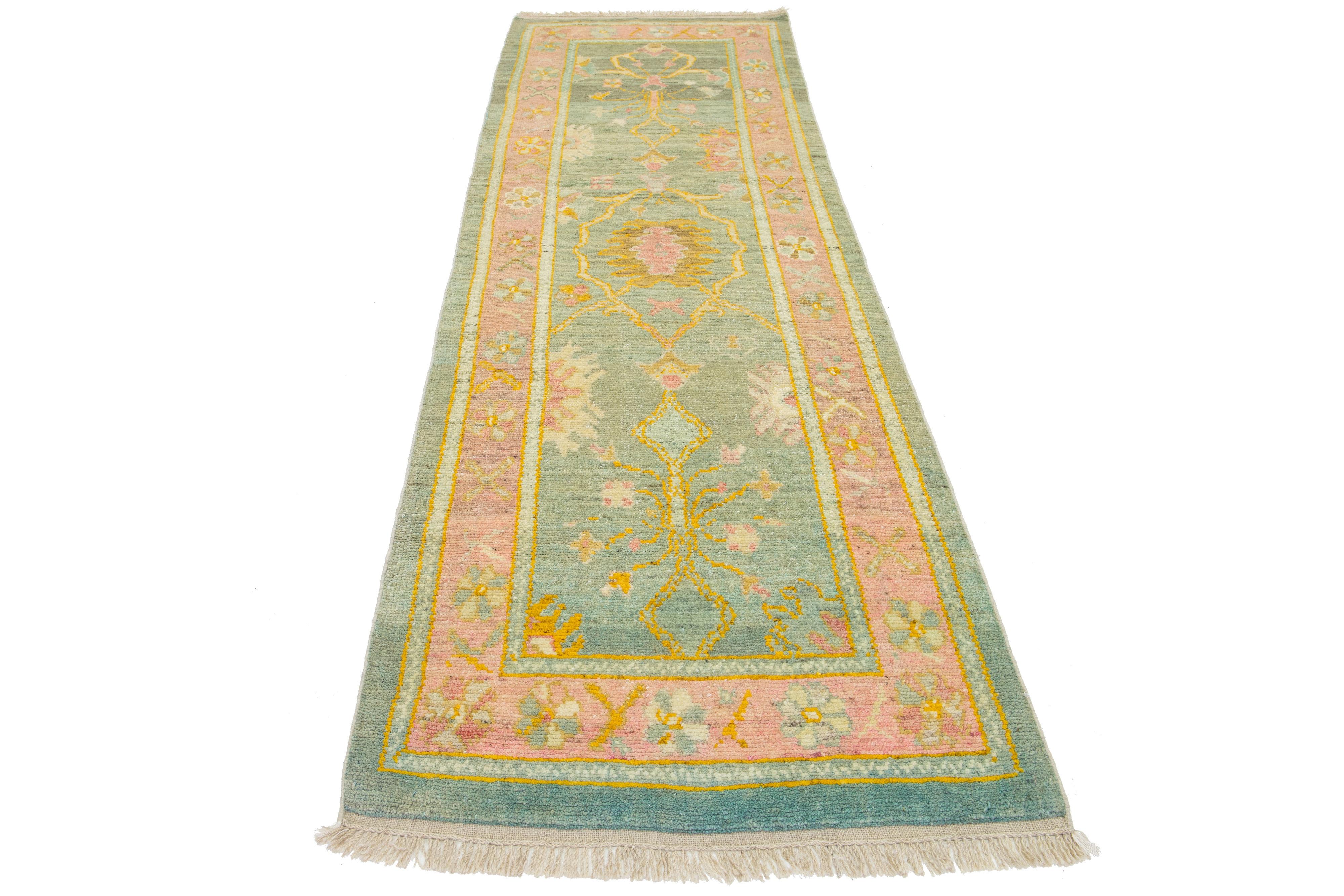 Beautiful modern Oushak hand-knotted wool rug with a green color field. This Turkish Piece has a pink frame with yellow, orange, pink, and green accent colors in a gorgeous all-over floral design.

This rug measures 2'11