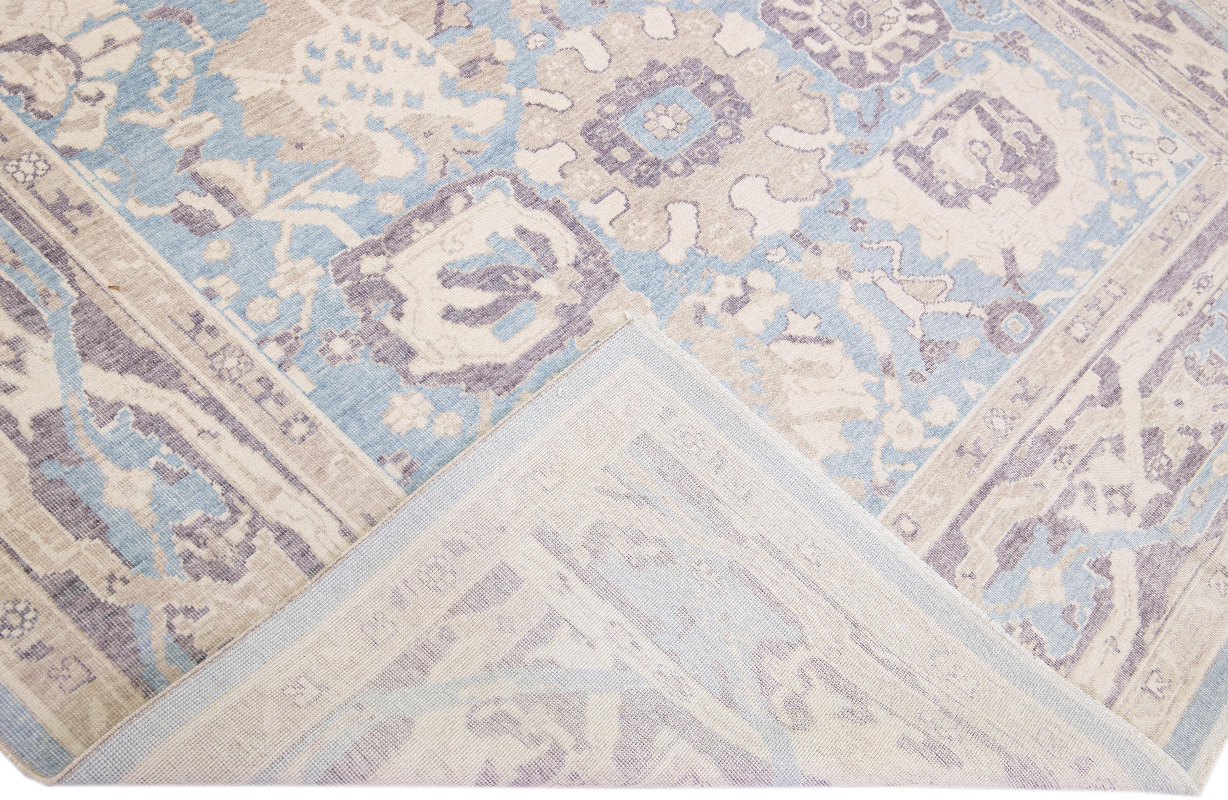Beautiful modern Oushak hand-knotted wool rug with a blue color field. This Turkish Piece has a purple frame with beige accent colors in a gorgeous all-over floral design.

This rug measures: 7'10