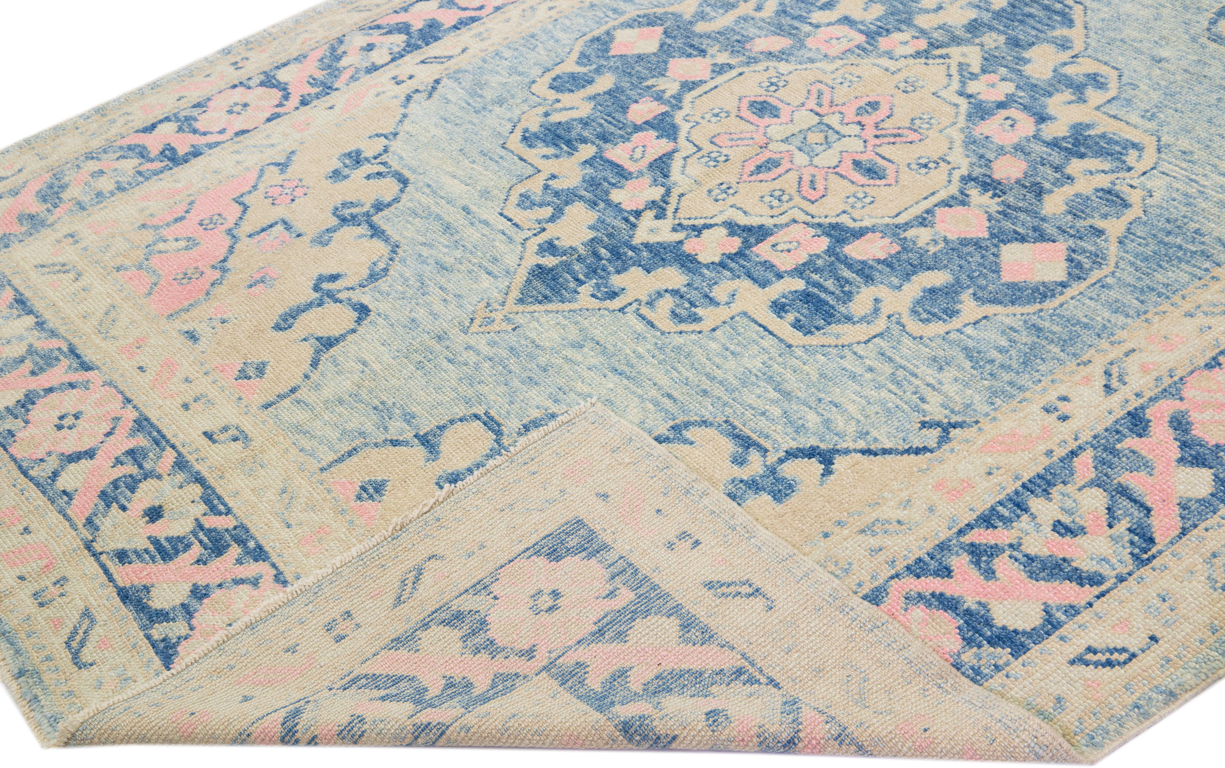 Beautiful modern Oushak hand-knotted wool rug with a light blue color field. This Turkish Piece has a navy blue frame with beige and pink accent colors in a gorgeous medallion floral design.

This rug measures: 6'9