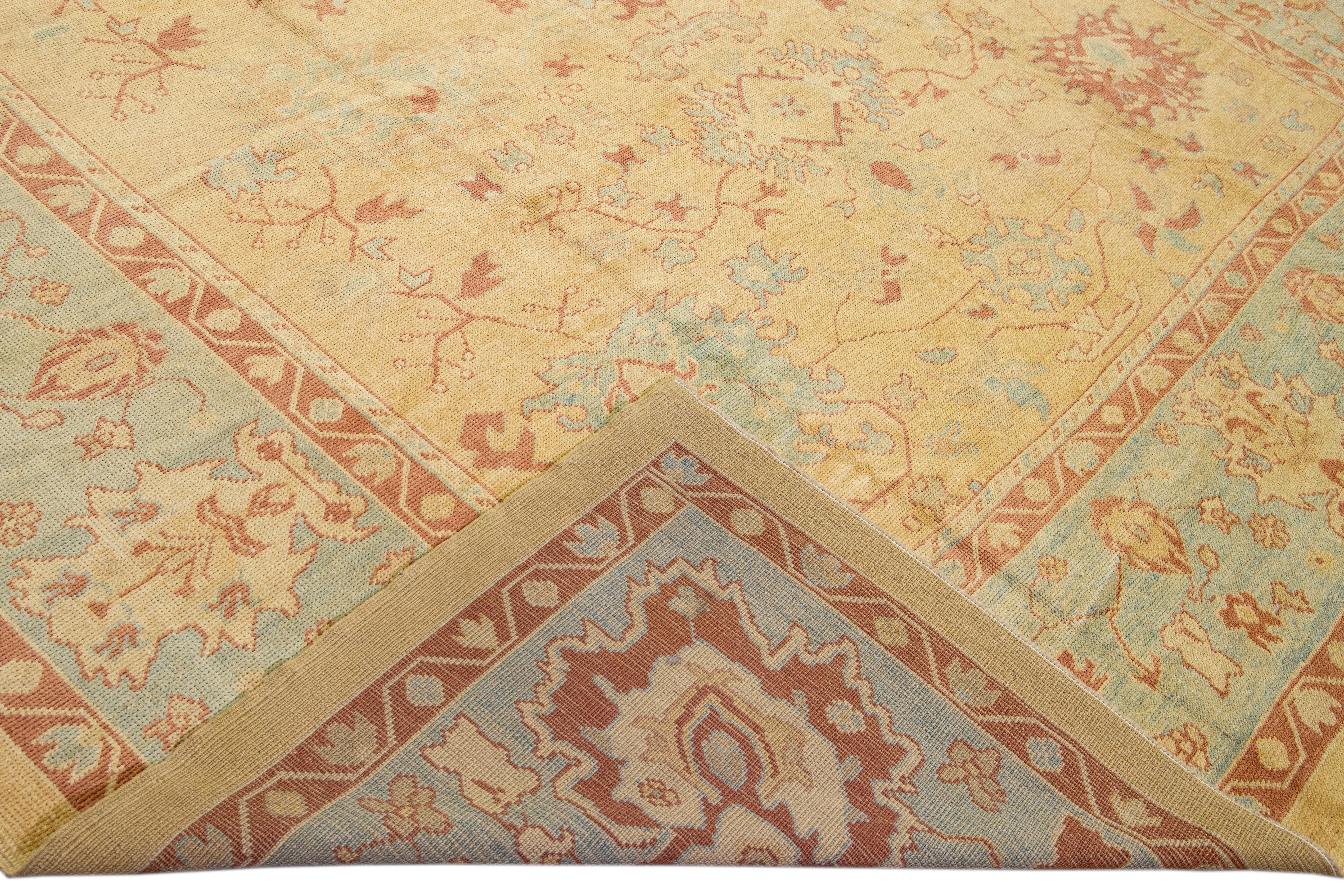 Beautiful modern Oushak hand-knotted wool rug with a goldenrod field. This Oushak rug has blue frame and terracotta accents that feature a gorgeous floral pattern design.

This rug measures: 11'9