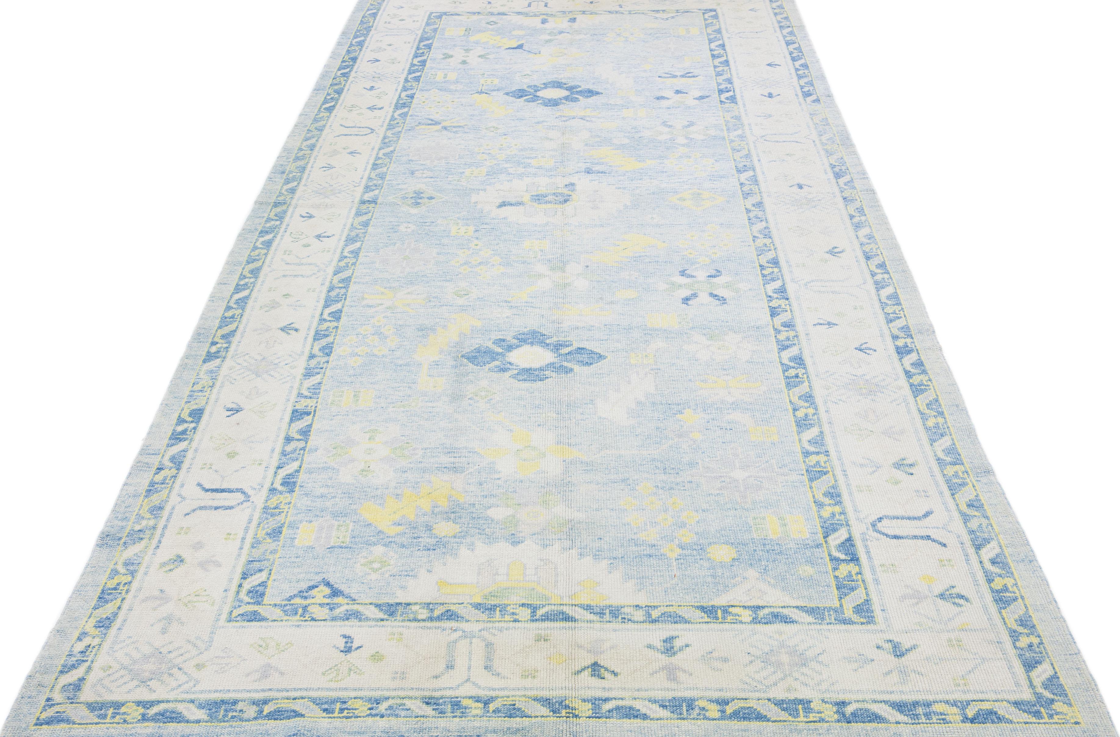 Beautiful modern Oushak hand-knotted wool rug with a light blue color field. This Turkish Piece has a gray frame with yellow and green accent colors in a gorgeous all-over floral design.

This rug measures: 6'11
