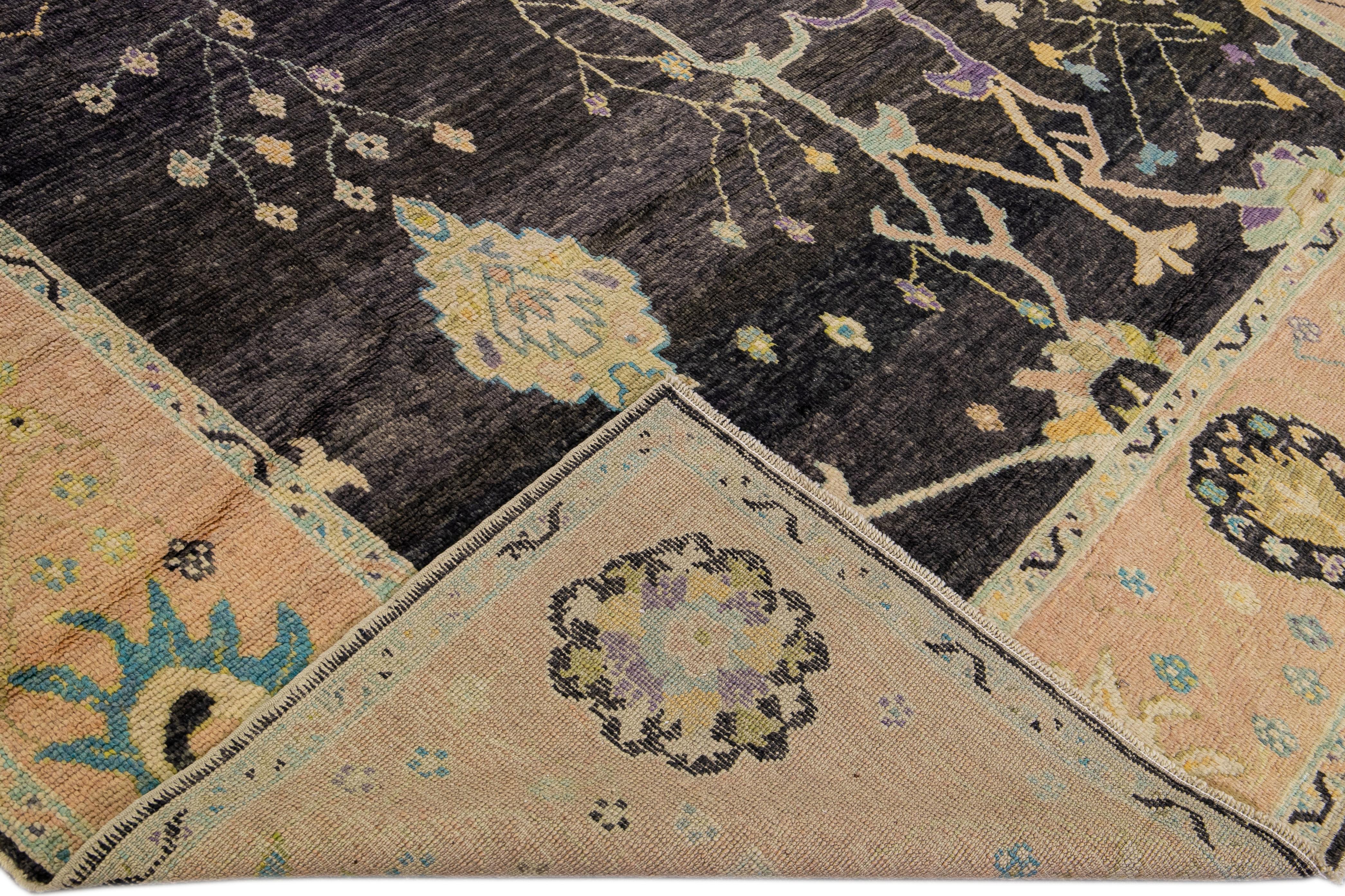 Schöner moderner Oushak-Teppich aus handgeknüpfter Wolle mit schwarzem Feld. Dieser Oushak-Teppich hat einen pfirsichfarbenen Rahmen und mehrfarbige Akzente auf einem wunderschönen geometrischen Blumenmotiv.

Dieser Teppich misst 9' x