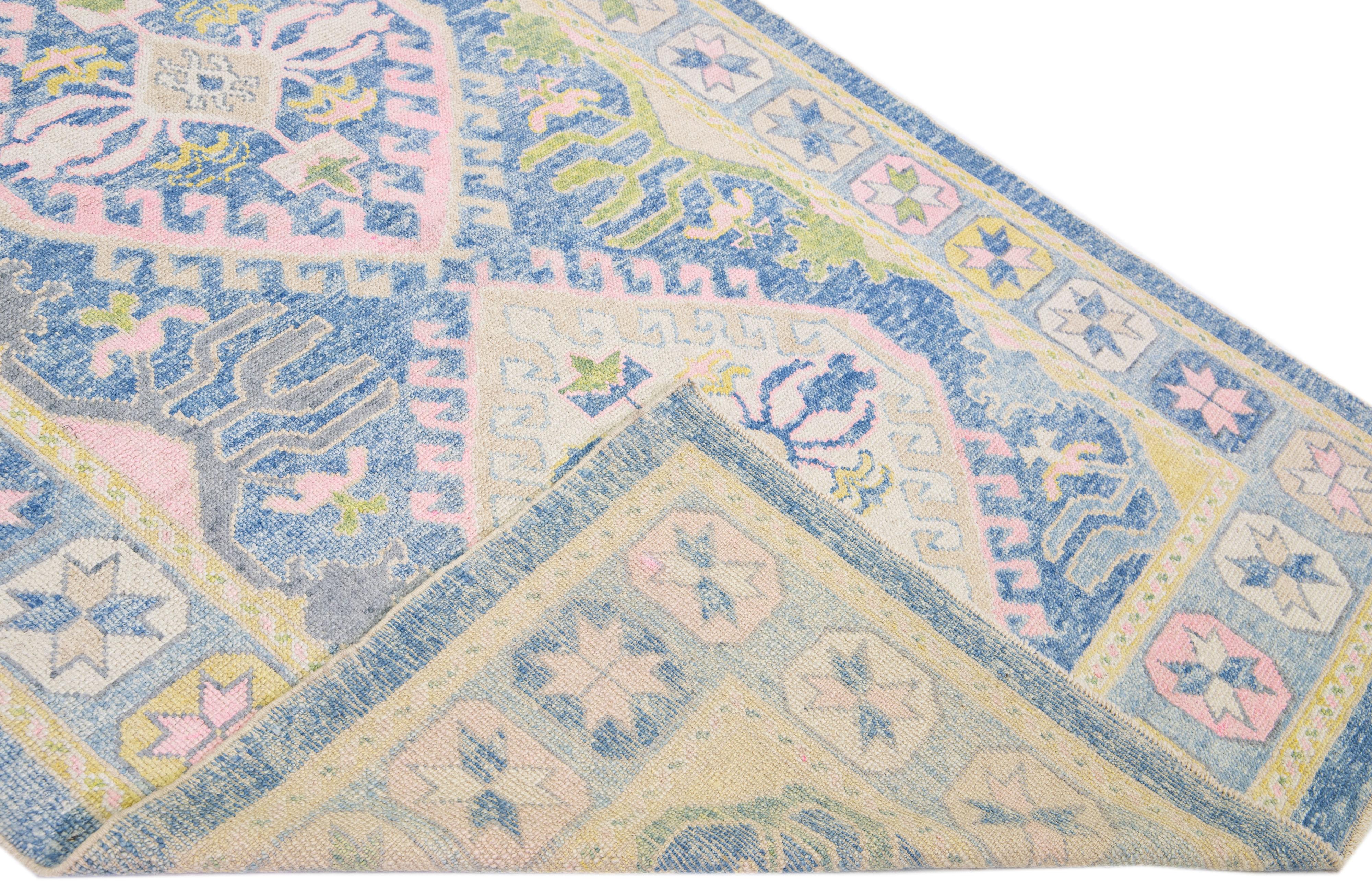 Beautiful modern Oushak hand-knotted wool rug with a blue color field. This Turkish Piece has yellow, gray, and pink accent colors in a gorgeous tribal design.

This rug measures: 6' x 16'7