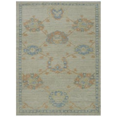 Tapis turc moderne Oushak avec têtes de fleurs en bleu et orange sur fond ivoire