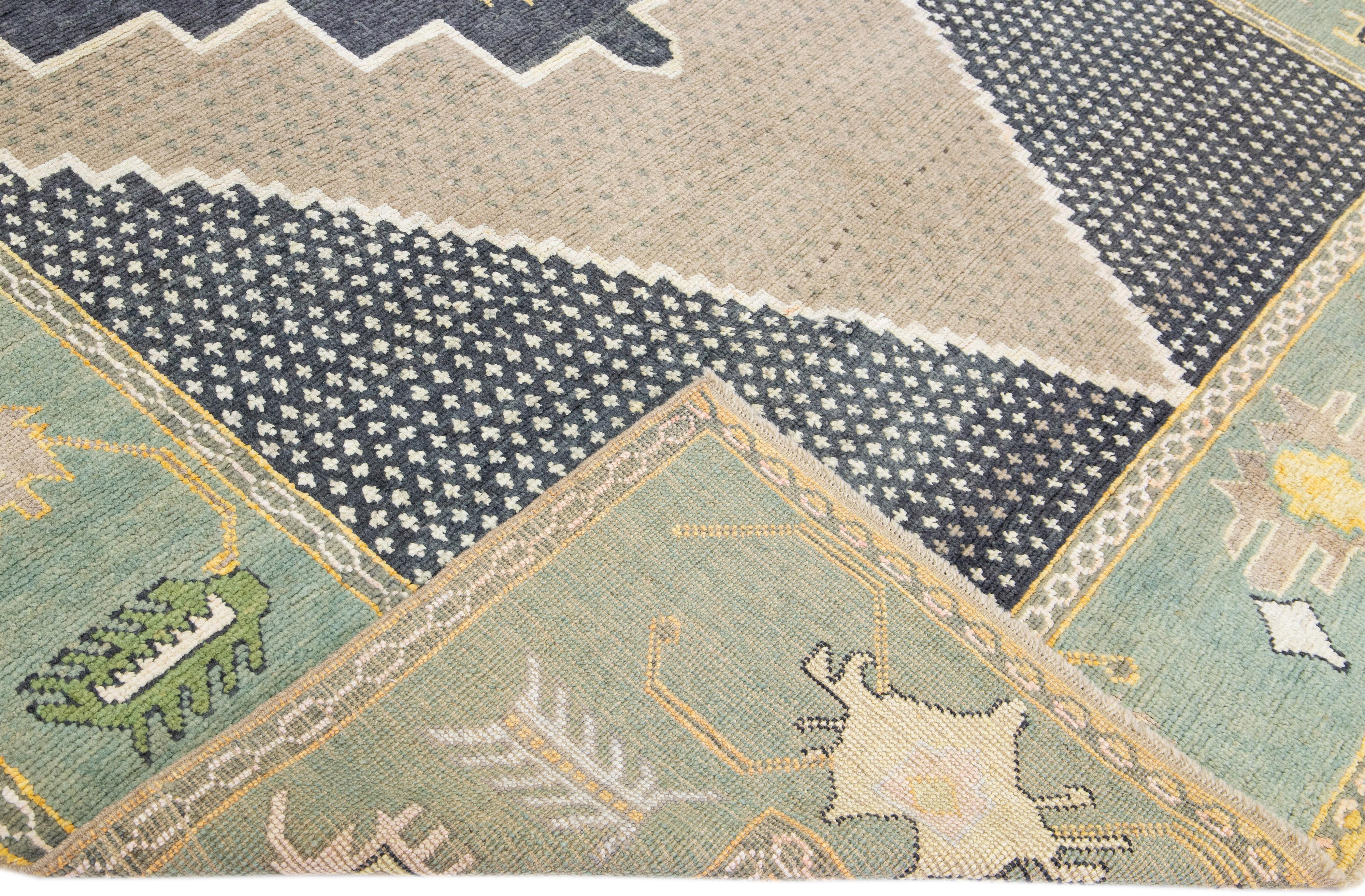 Beautiful modern Oushak hand-knotted wool rug with a tan and gray field. This Oushak rug has a green-designed frame and accents of orange, yellow, and ivory all over a gorgeous geometric medallion design.

This rug measures: 8'3