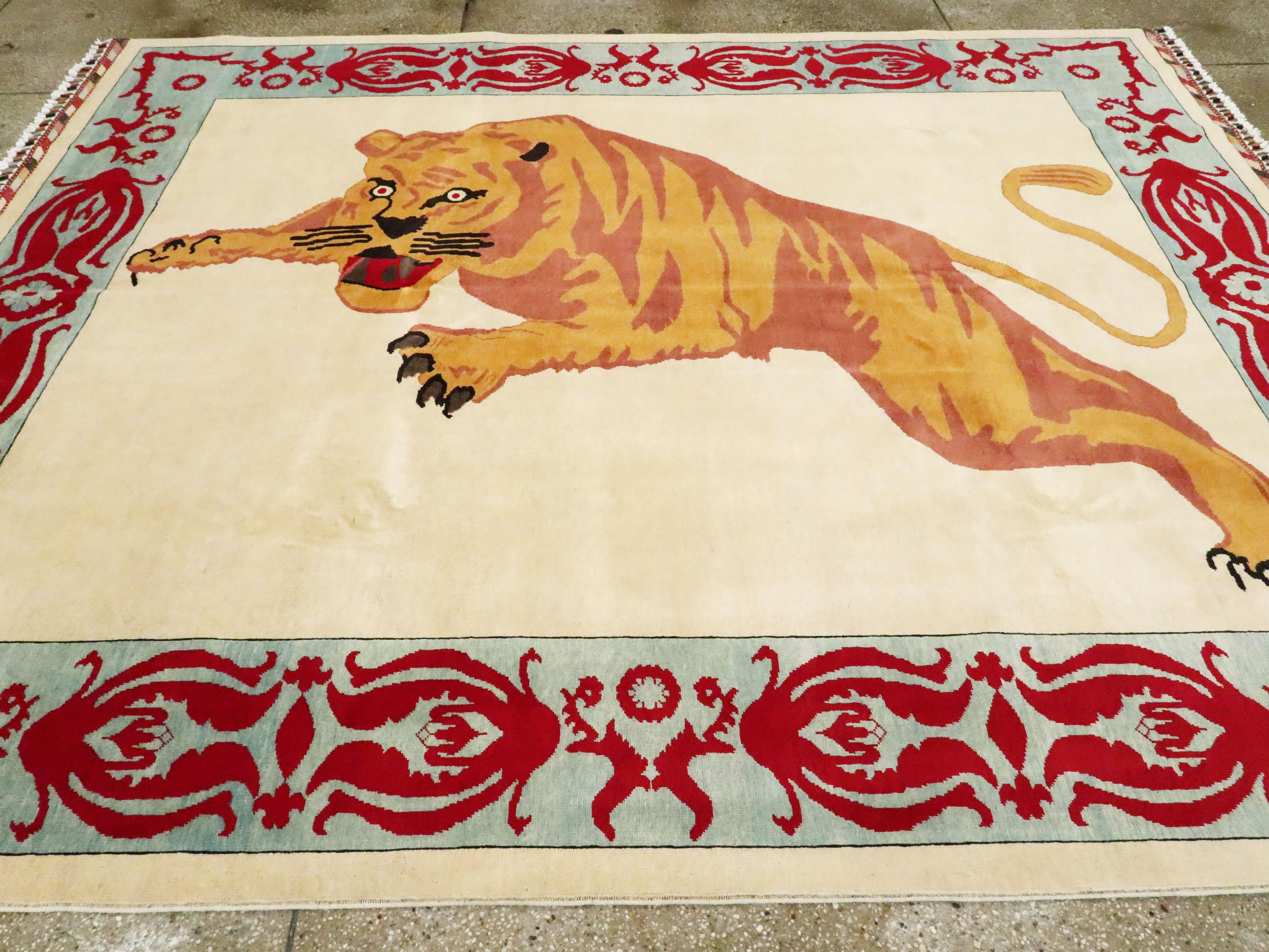 A modern Turkish pictorial carpet of a pouncing tiger from the 21st century. The tiger sits atop an ivory field enclosed with a seafoam blue border with large floral motifs in red.

Measures: 8' 1
