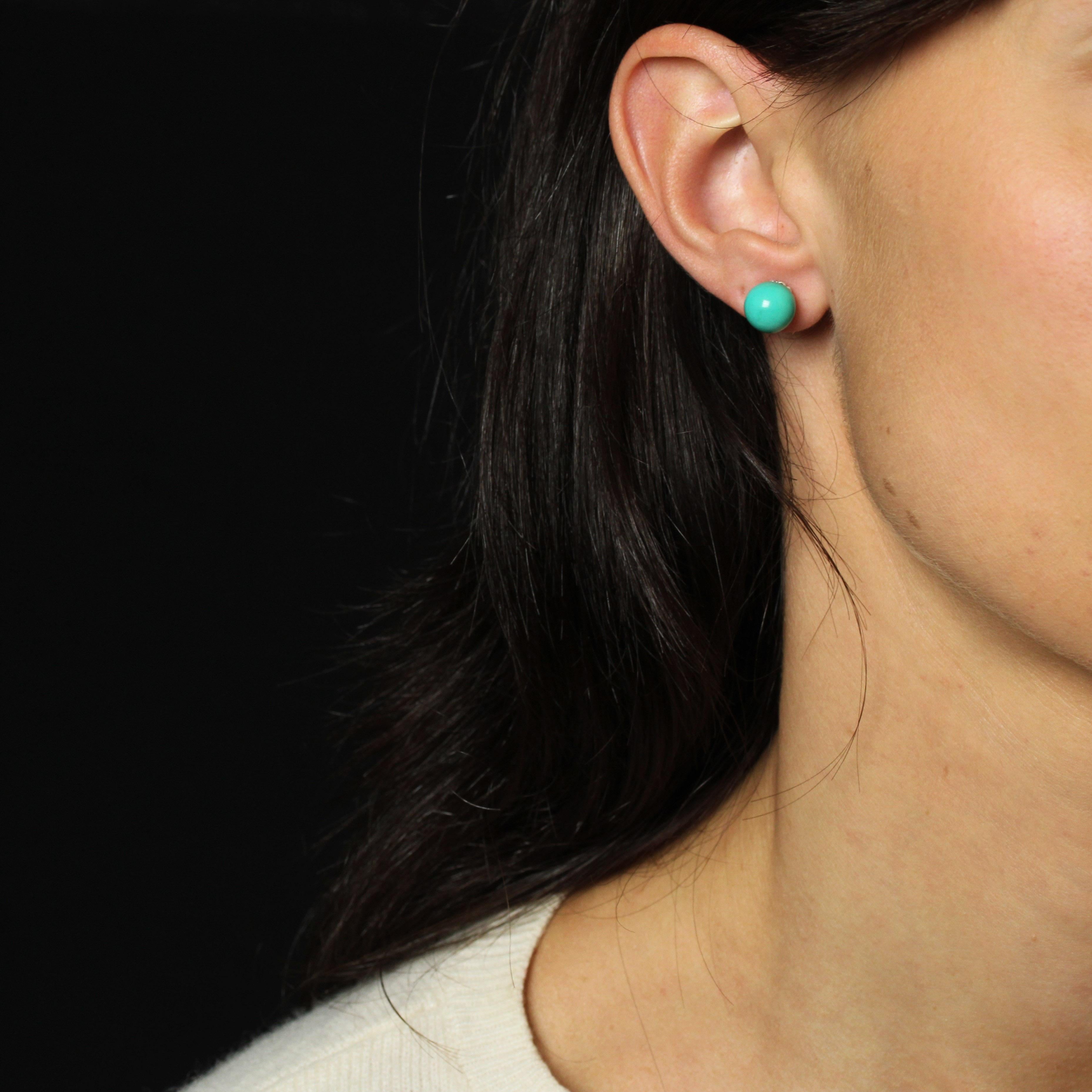 For pierced ears.
Earrings in 18 karat white gold.
Charming pair of earrings featuring a turquoise stone bead held in place by a white gold stem whose base forms a corolla. The clasp is a butterfly.
Diameter of the bead : 9/9.5 mm approximately,