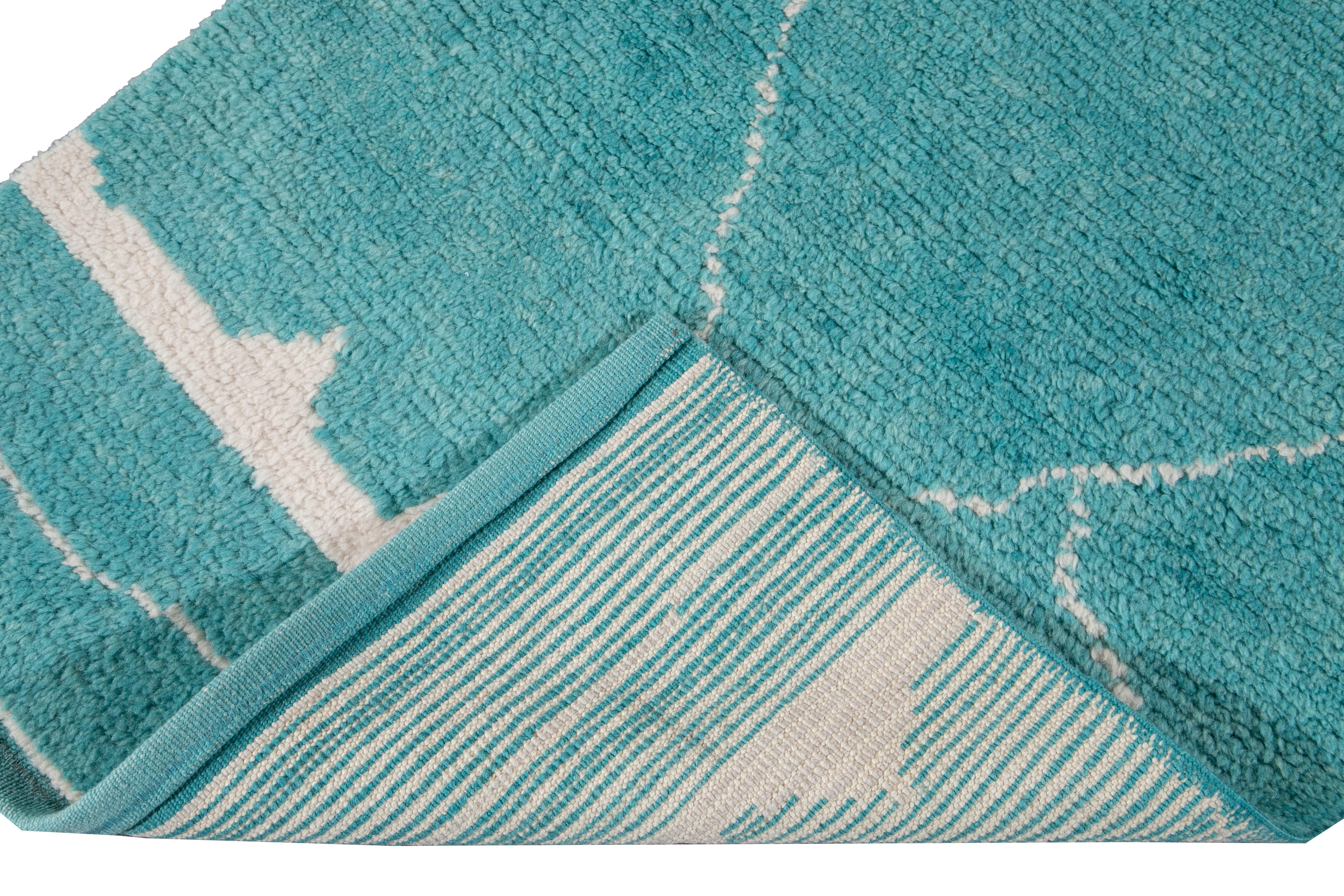 Magnifique tapis contemporain de style marocain en laine nouée à la main avec un champ turquoise. Ce tapis moderne présente un accent ivoire dans un magnifique motif géométrique tribal.

Ce tapis mesure : 2'11