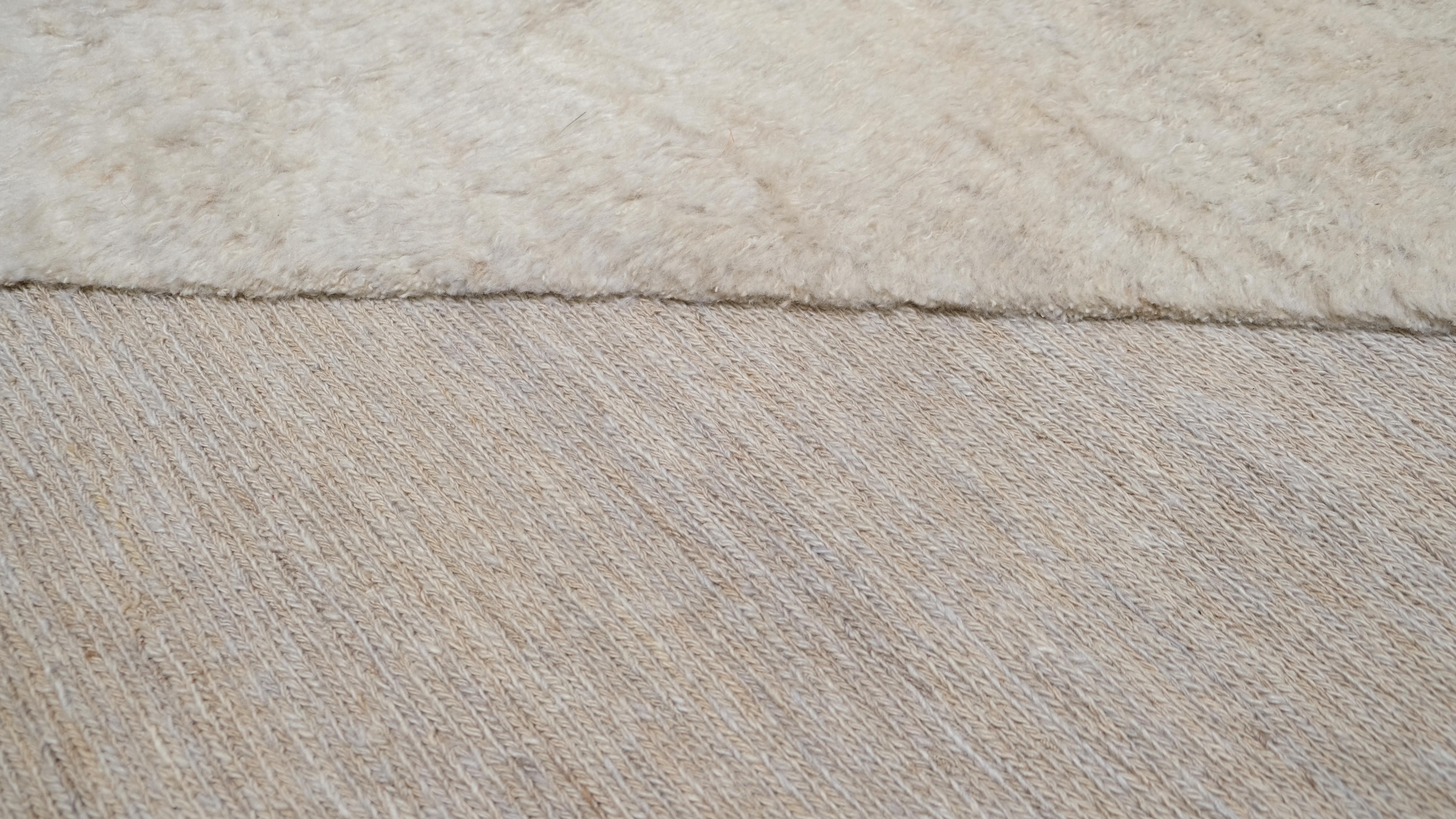 Dieser raffinierte, handgeknüpfte Wollteppich mit seinem einzigartigen, zweifarbigen, geometrischen Muster wertet Ihren Wohnbereich auf. Der minimalistische Stil und die neutrale Farbpalette machen diesen Teppich zu einem vielseitigen Stück, das