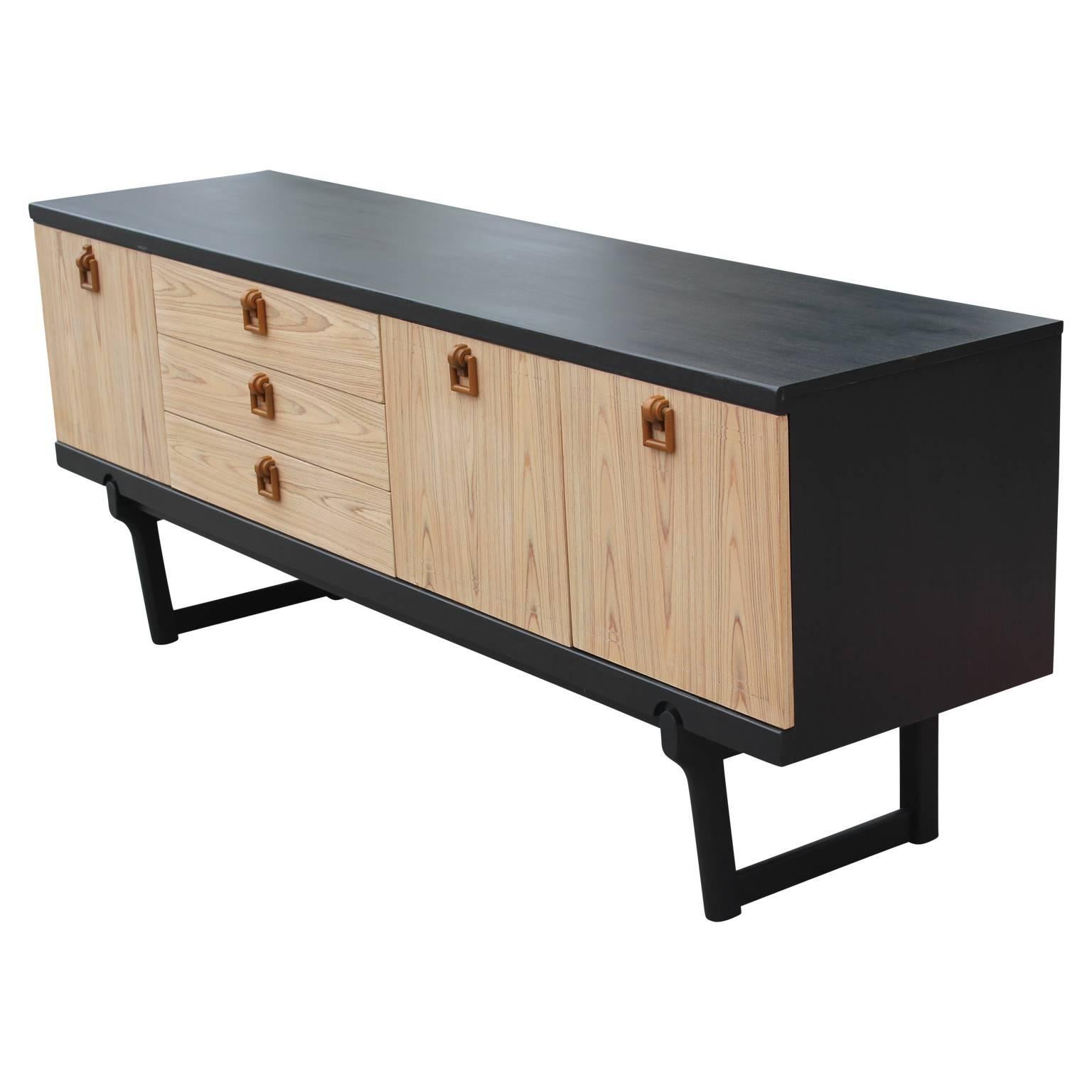 Modern two-tone credenza or sideboard refinished in charcoal and with a bleached front. Outfitted with bakelite handles. The left door opens to reveal a single shelf, the middle section has three doors and the right doors open to reveal an open