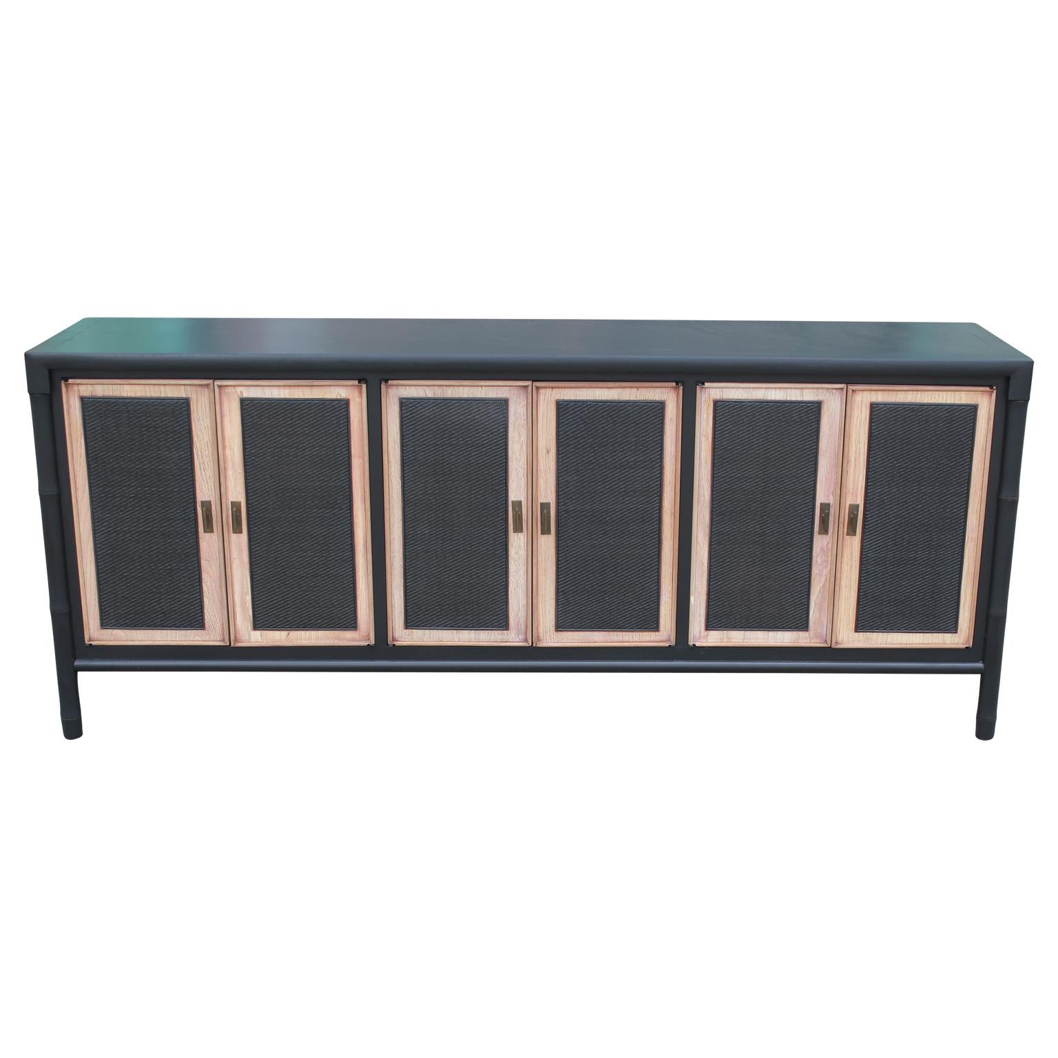 Gorgeous Mid-Century Modern credenza freshly refinished in a two-tone style with brass hardware, cane paneled fronts and faux bamboo sides. This piece opens to reveal three drawers and varied cabinet spaces.