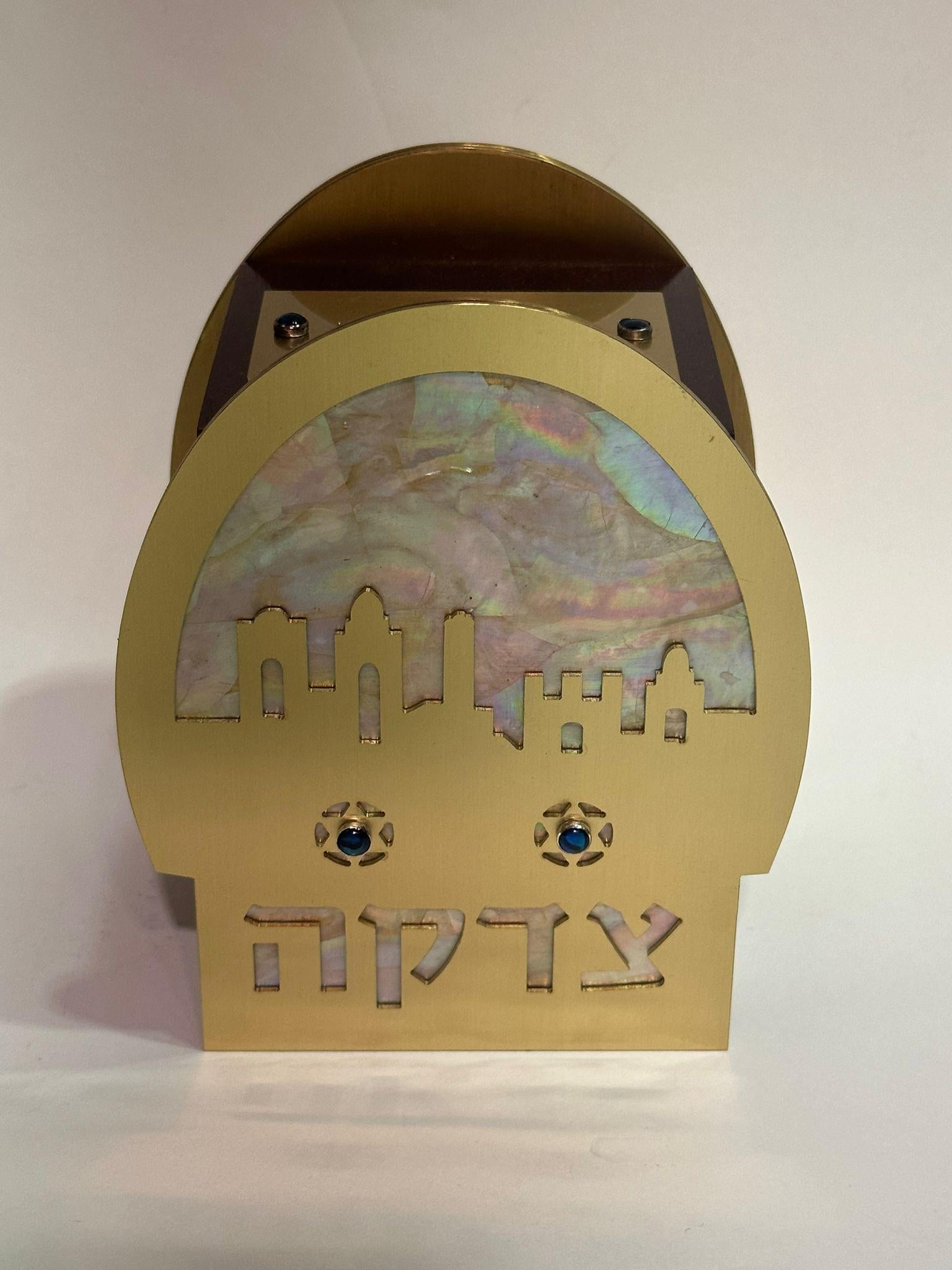 Cette boîte de tzedakah (charité), fabriquée en 2000 par Lorelei et Alex Gruss, artistes basés à Brooklyn, est un exemple exquis de l'art judaïque. Le design présente la silhouette d'un paysage urbain, évoquant vraisemblablement Jérusalem, réalisée