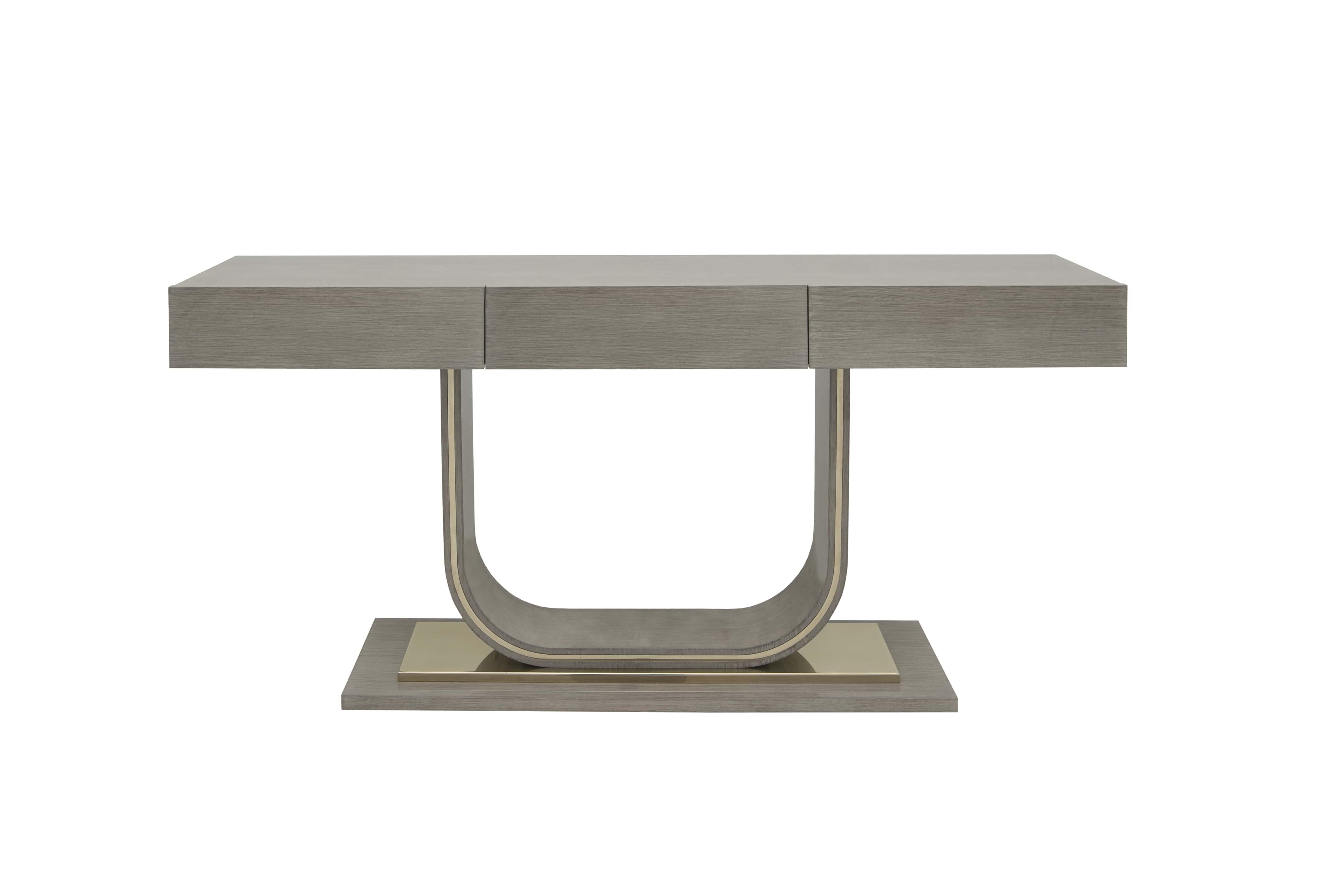 Elegante e sofisticato, questo moderno tavolo consolle presenta un piano rettangolare e pulito sostenuto da una base a forma di U. Rifinito in una morbida tonalità di legno neutro con sottili accenti metallici, dona un'eleganza moderna a qualsiasi