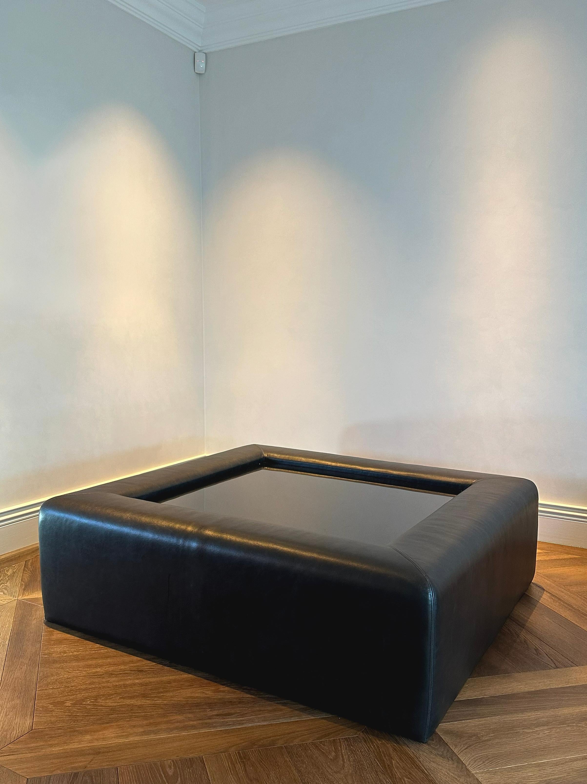 This modernist upholstered coffee table was handcrafted in London in 2014 by a fine furniture maker, reflecting the pared-back elegance of 1970s modern design. The generous square form is fully upholstered in anthracite cowhide leather, offering a