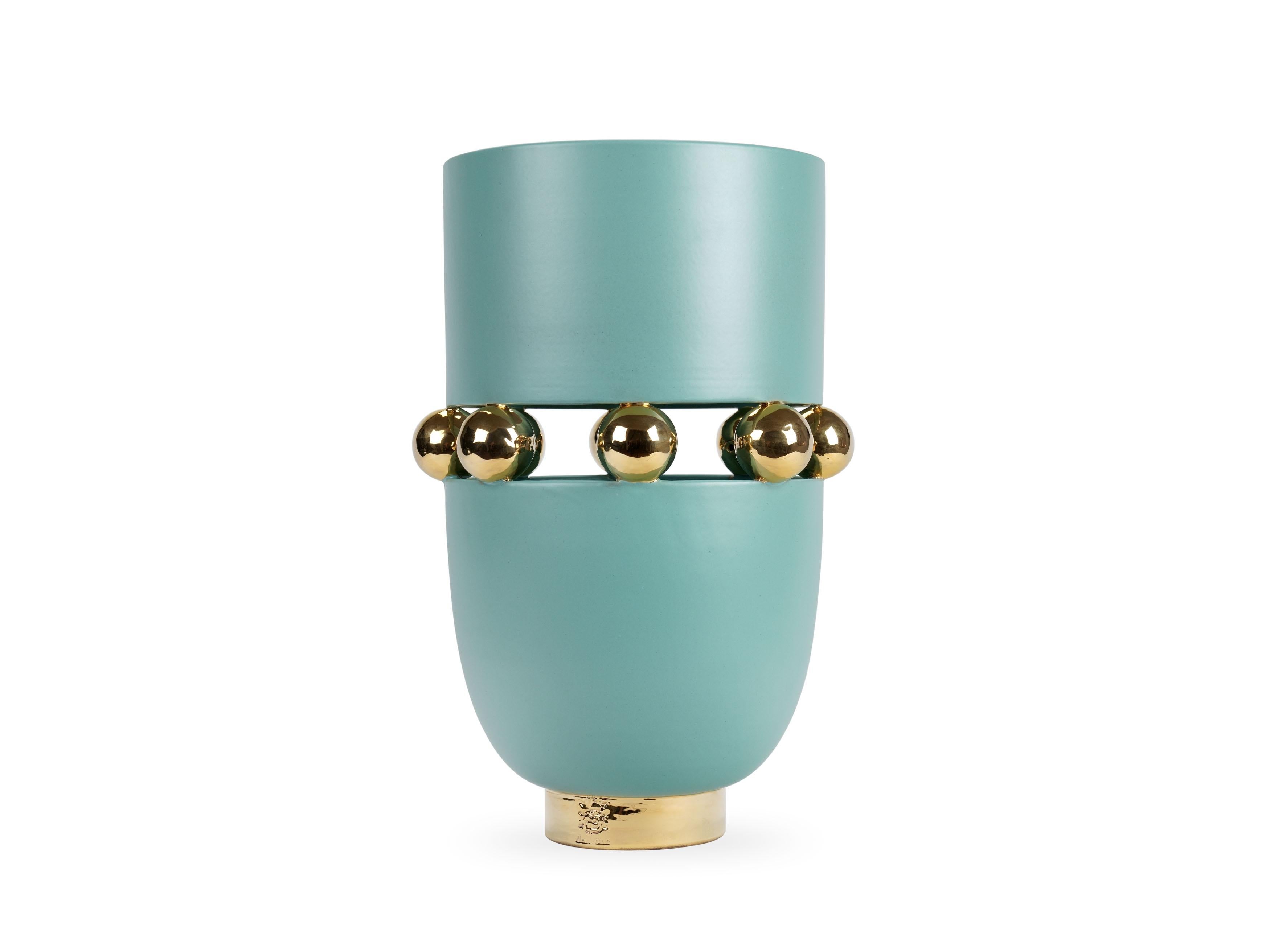 Elegant aquamarine vase with a matte finishing, alternating with reflective surfaces embellished with 24Kt gold luster. This technique sees ceramics to undergo three cooking phases: the last one, called third firing, lets the gold luster release its