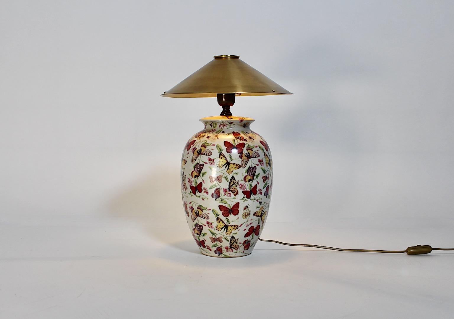 Modern vintage table lamp from ceramic and brass with multicolored printed butterfly and flowers decor 1980s.
This amazing and feminine table lamp from ceramic and brass shows a ceramic body full of printed multicolored butterflies and flowers,
