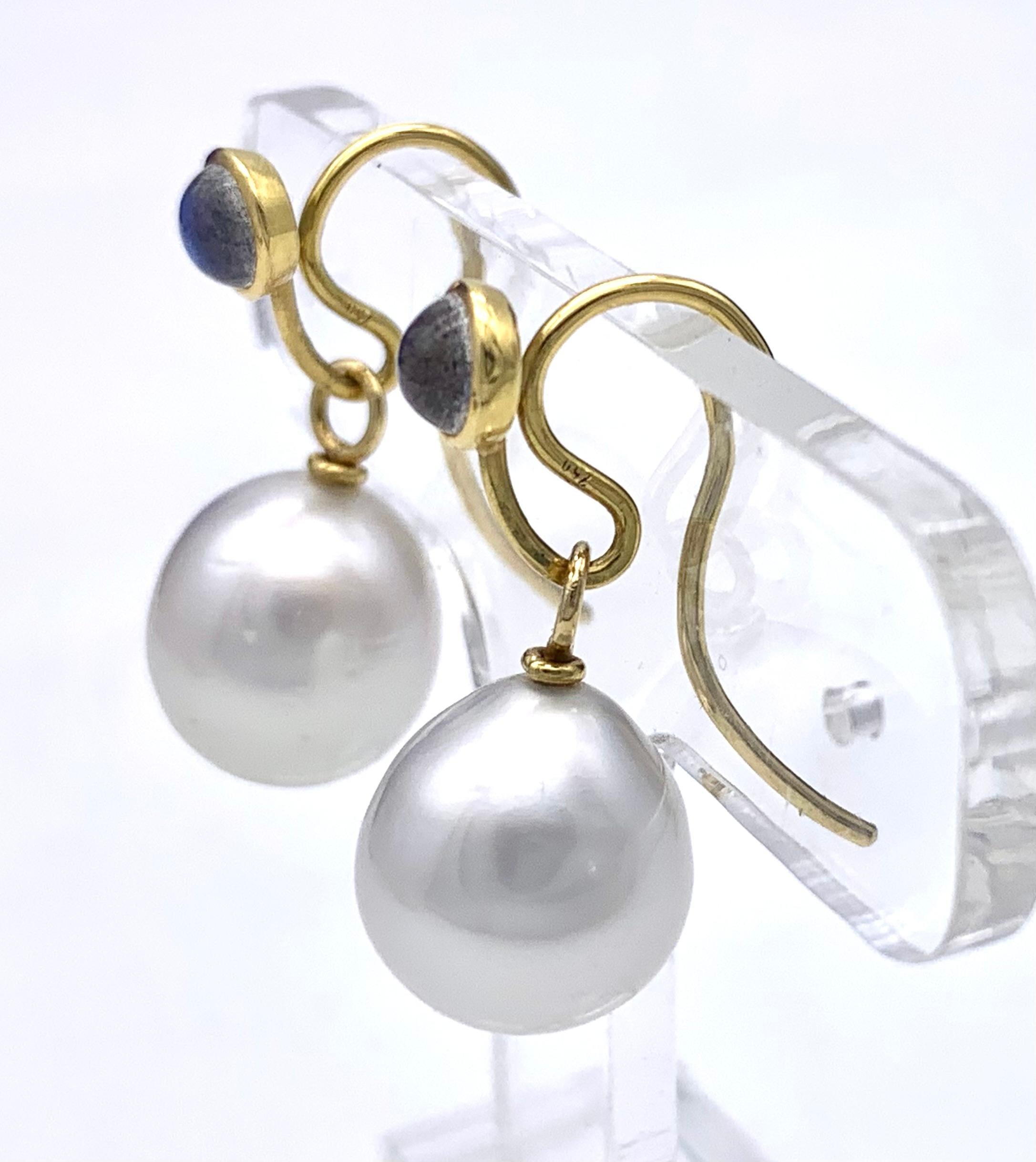 This wonderful pair of white South Sea pearl drop dangle earrings are suspended from gold wires decorated with moonstone cabochons mounted in 18 karat yellow gold. The pearls have a fine even luster. The hooks are impressed with 750 for 18 karat.   