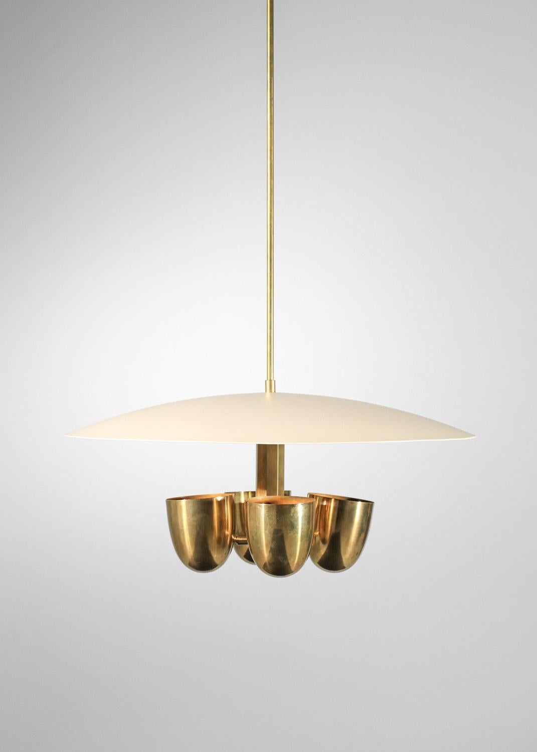 This modern chandelier is composed of an off-white lacquered metal dome and four bell shades in patinated solid brass. The lower central hexagonal bar is also made of solid brass. We recommend four E14 type LED bulbs for this chandelier. Possibility