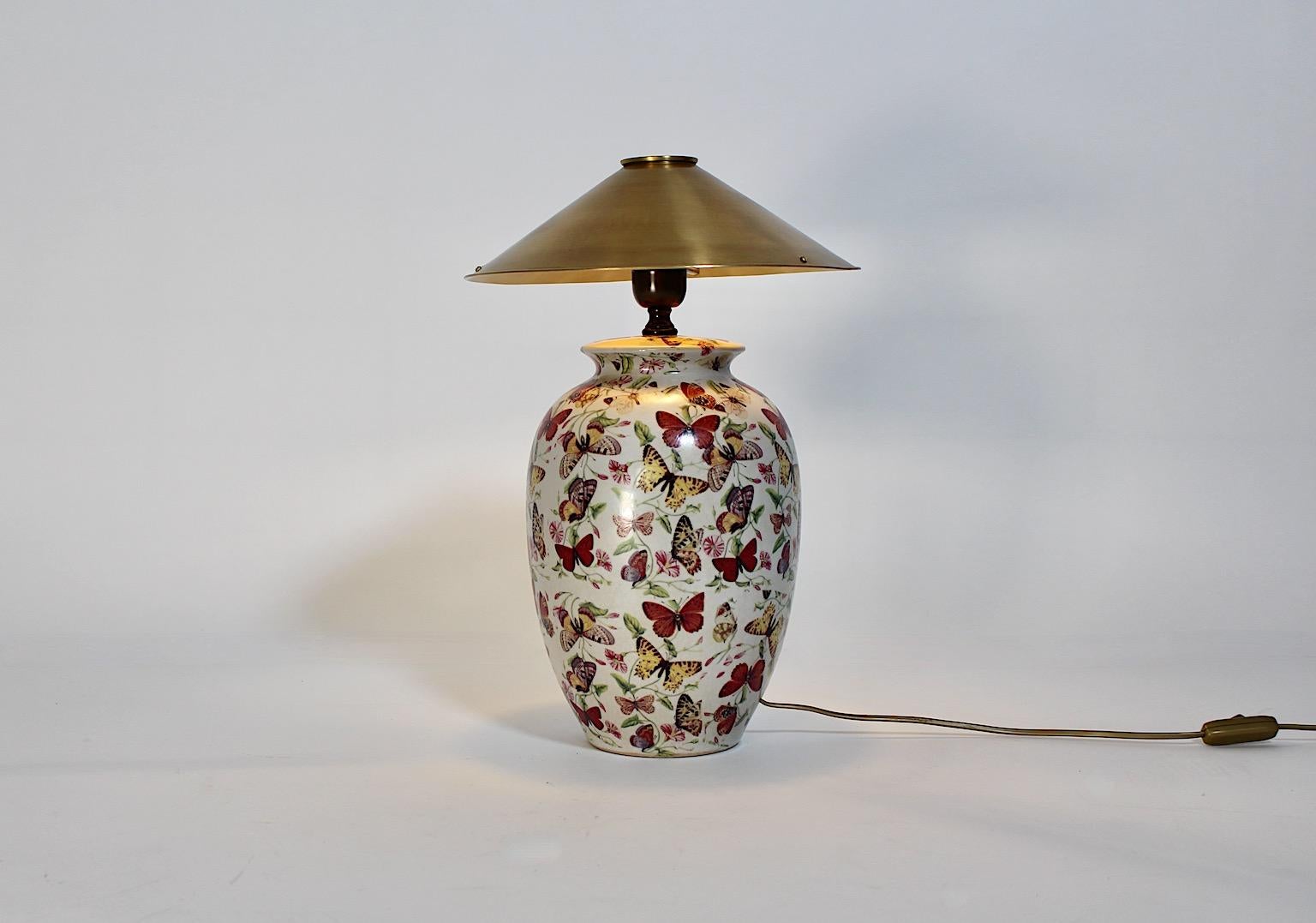 Modern vintage table lamp from ceramic and brass with multicolored printed floral and fauna butterfly and flowers decor 1980s.
This amazing and charming table lamp from ceramic and brass shows a ceramic body full of printed multicolored butterflies