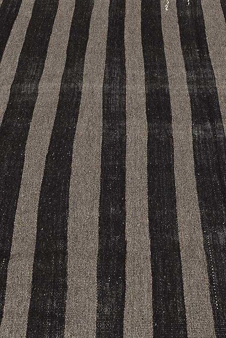 This vintage Kilim is simple in design yet so elegant with its deep dark brown and beige color palette. The horizontal lines are impeccably woven in the fabric, showcasing the masterful weaver's experienced hand. This design captures both, elegance
