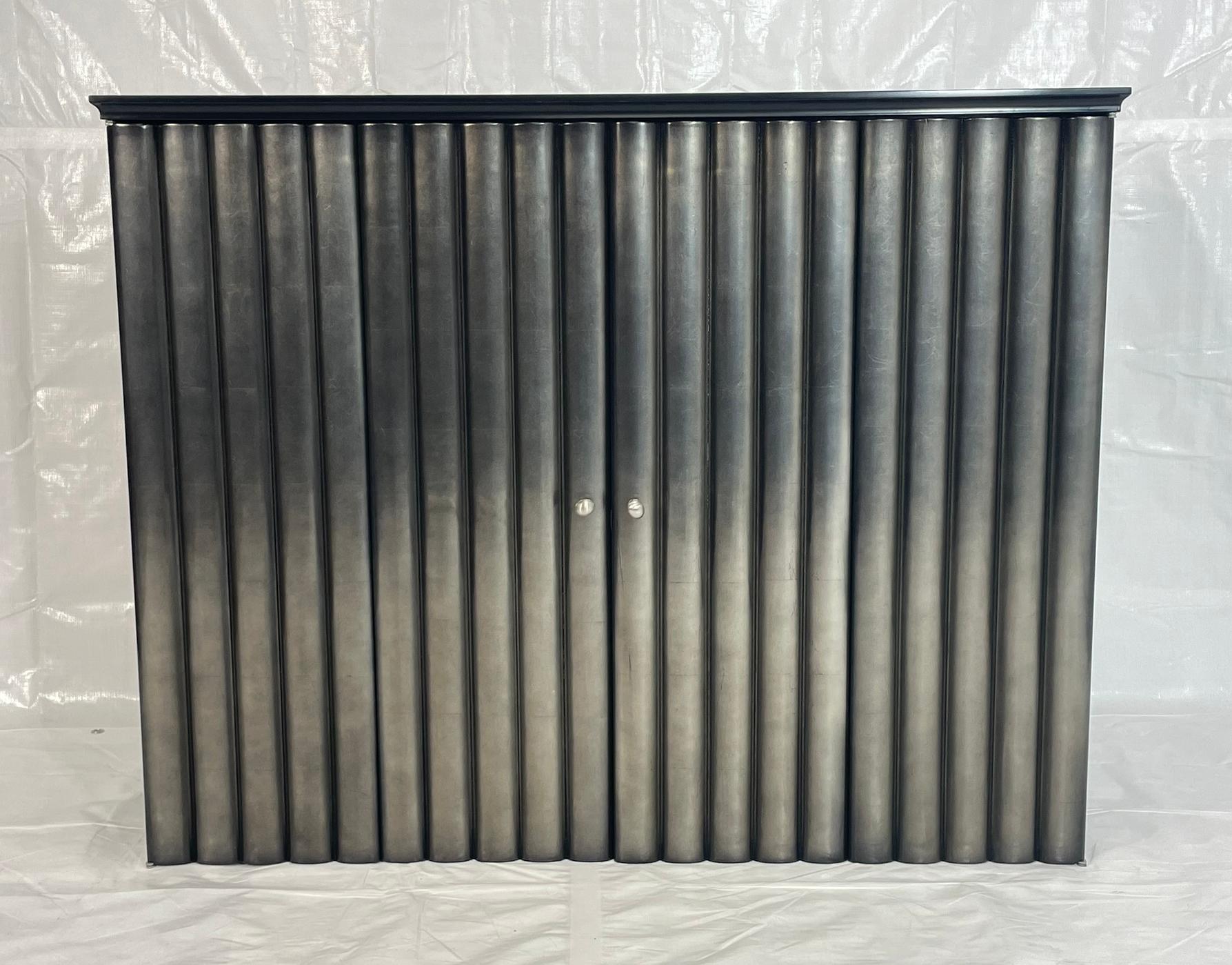 Elegante y escultural, este moderno armario de pared presenta una distintiva fachada de puertas plegables acanaladas acabadas en un elegante degradado metálico, que combina forma y función con refinada sofisticación.

Las limpias líneas