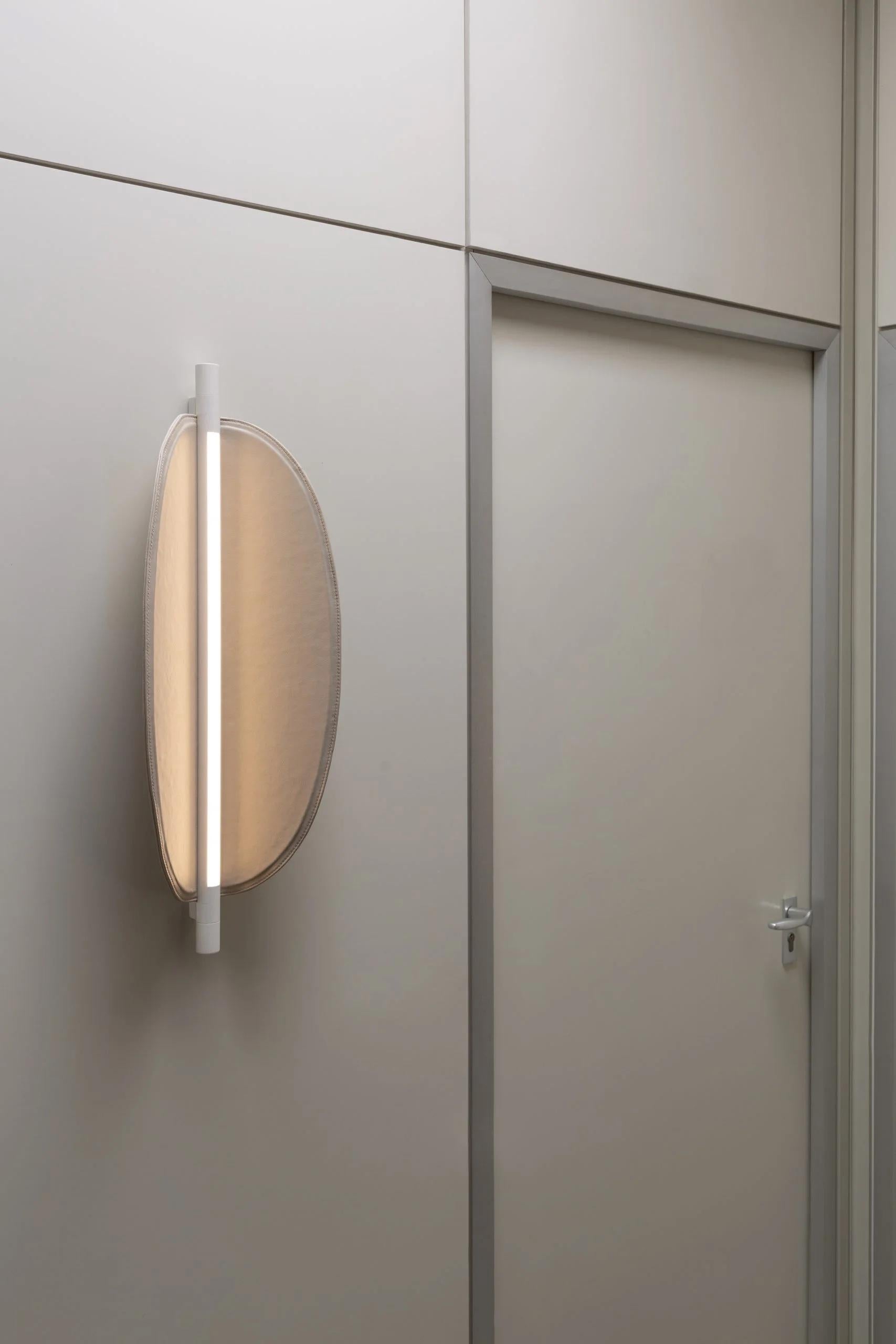 Thula 562.41 by Frederica Biasi x Tooy
Wall lamp
Compliant with USA electric system

Model shown: 
- hardware Beige 
- details Beige
- shade Leather beige

Materials: aluminum, metal, leather, wood

The Thula wall lamps are based on a simple and