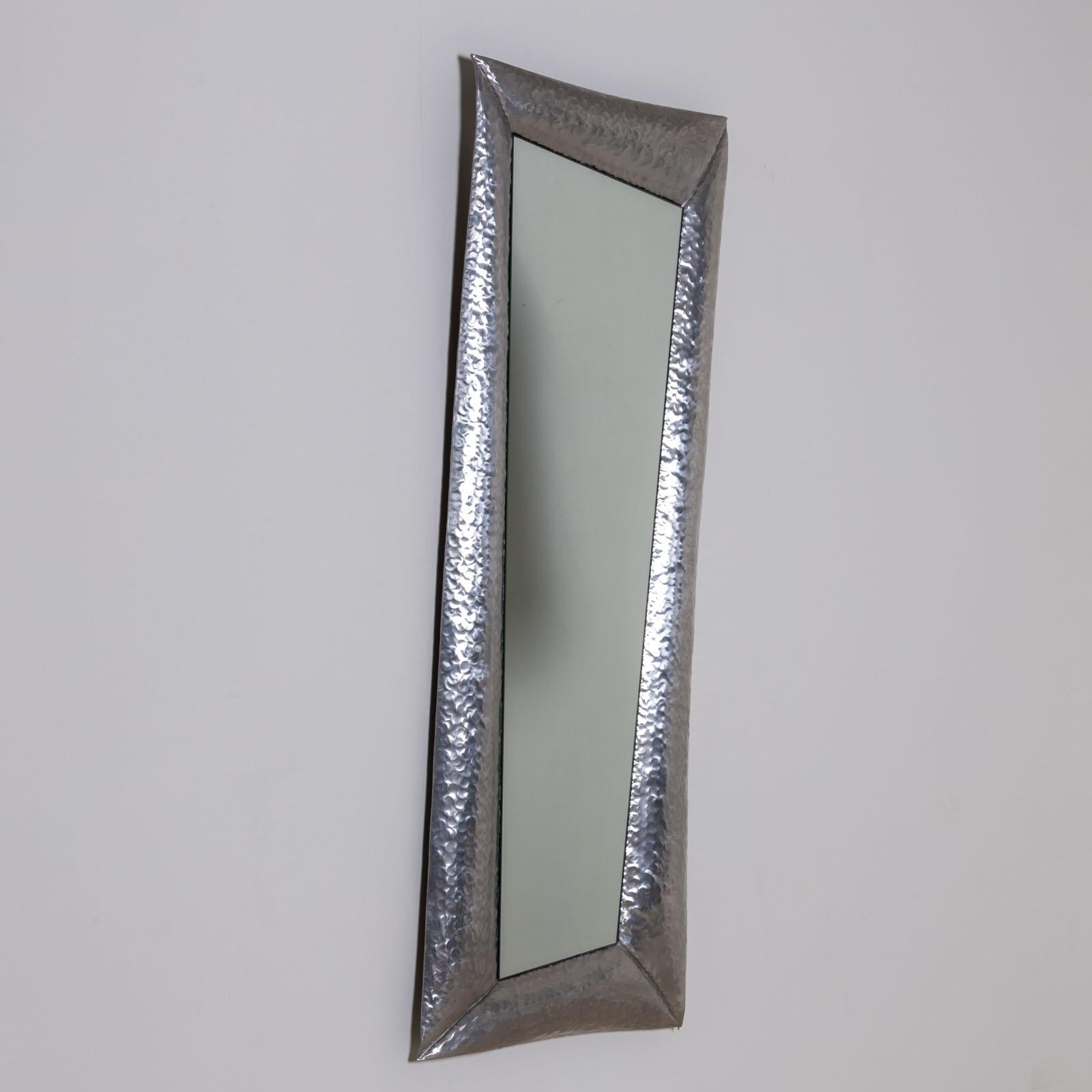 Miroir mural artisanal dans un cadre asymétrique en aluminium de l'artiste italien Marco MarCo. Le cadre a une surface martelée et est étiqueté et signé au dos. La partie lisible indique : 