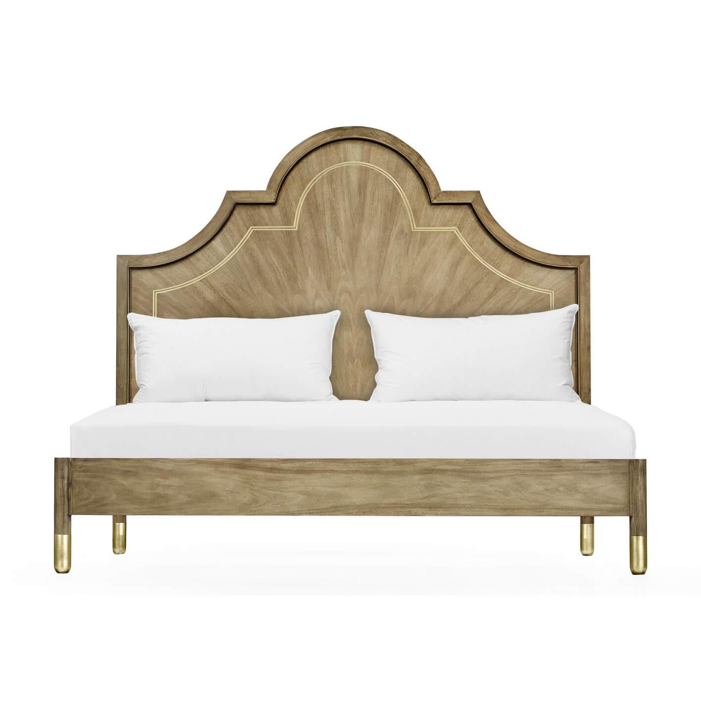 A modern walnut and brass inlaid king size bed. The arched headboard with bleached figured walnut inlaid with brass trim and raised on a walnut frame with turned legs and brass feet.

Dimensions: 81.5