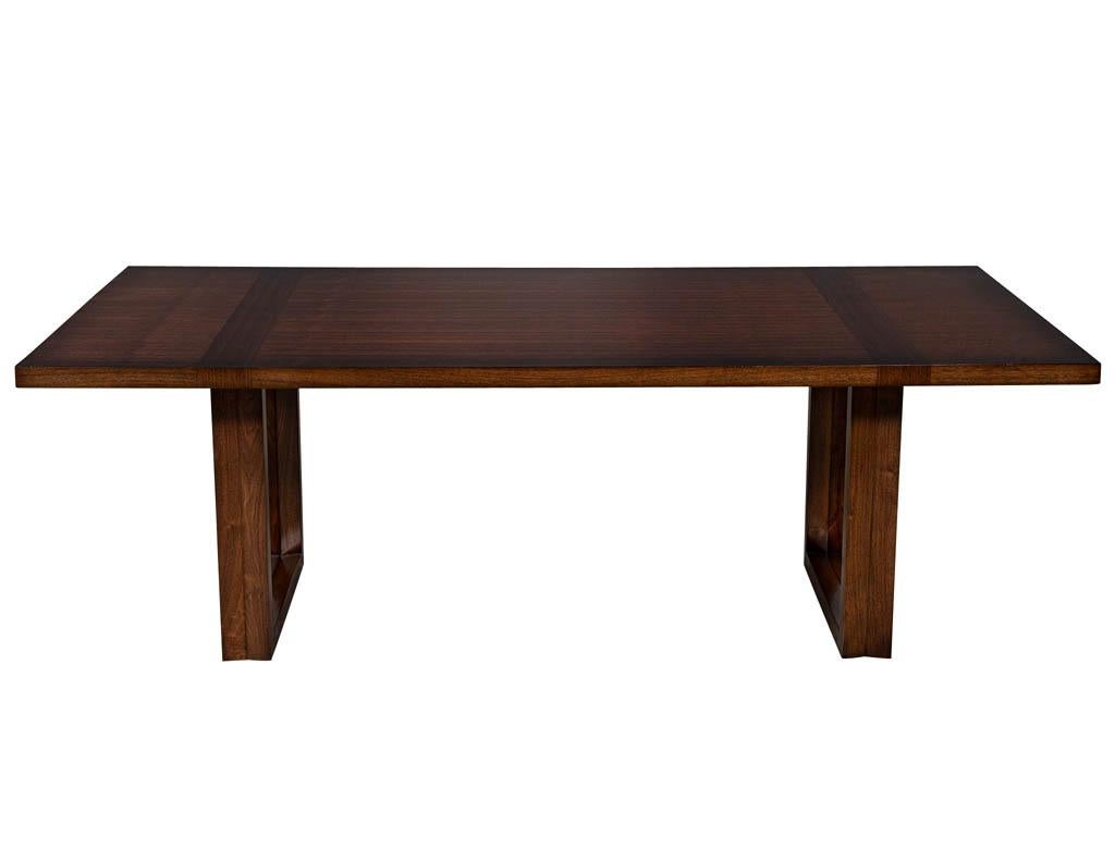 Modern walnut dining table with geometric bases. Featuring rich satin walnut finish with contrasting bands and two contoured geometric bases.

Price includes complimentary scheduled curb side delivery service to the continental USA.