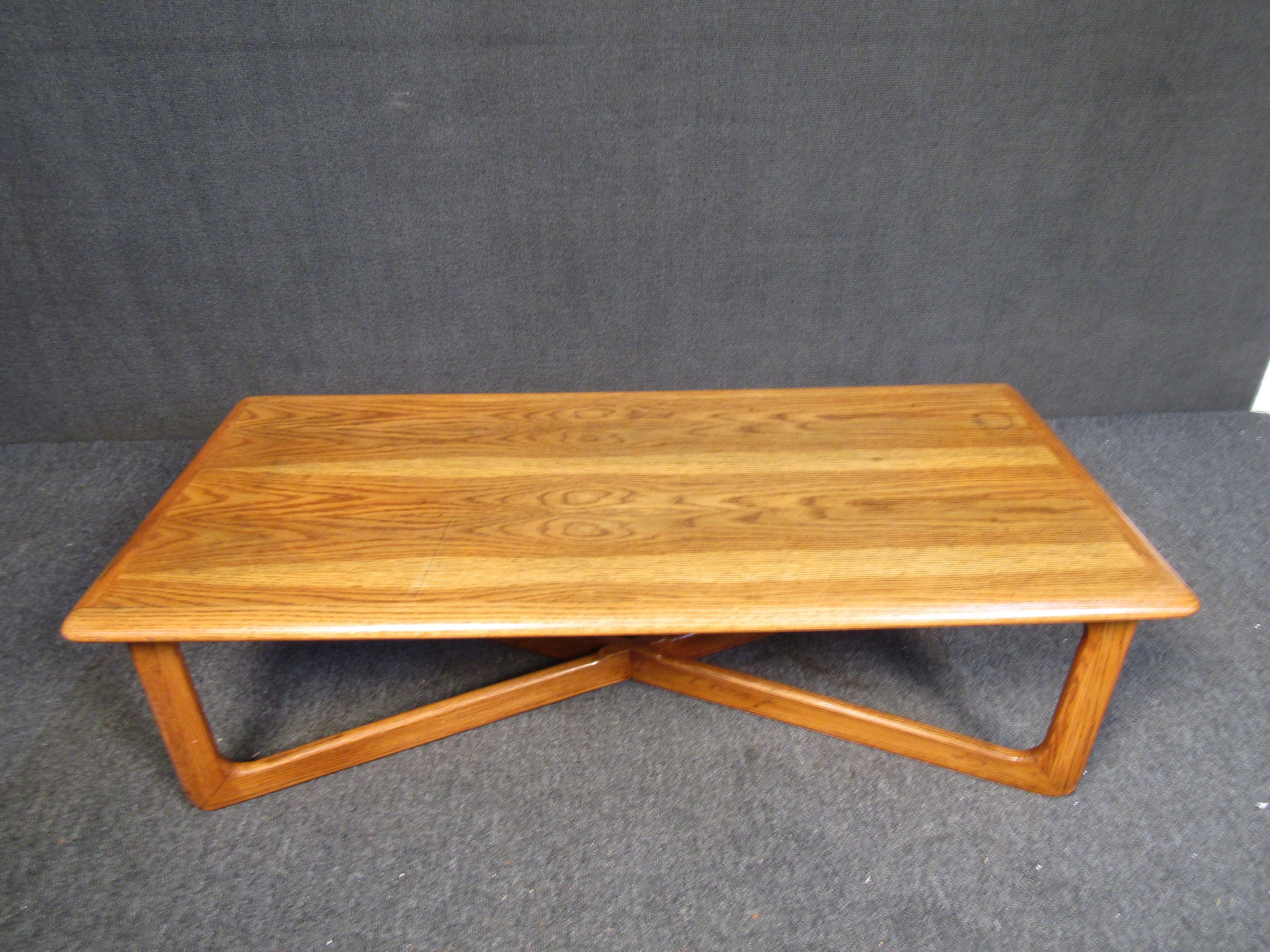 Mid-Century Modern walnut coffee table with an X base and rounded edges. Well constructed and retains the branding mark to the bottom, manufactured by the Lane furniture company. Please confirm item location with seller (NY/NJ).