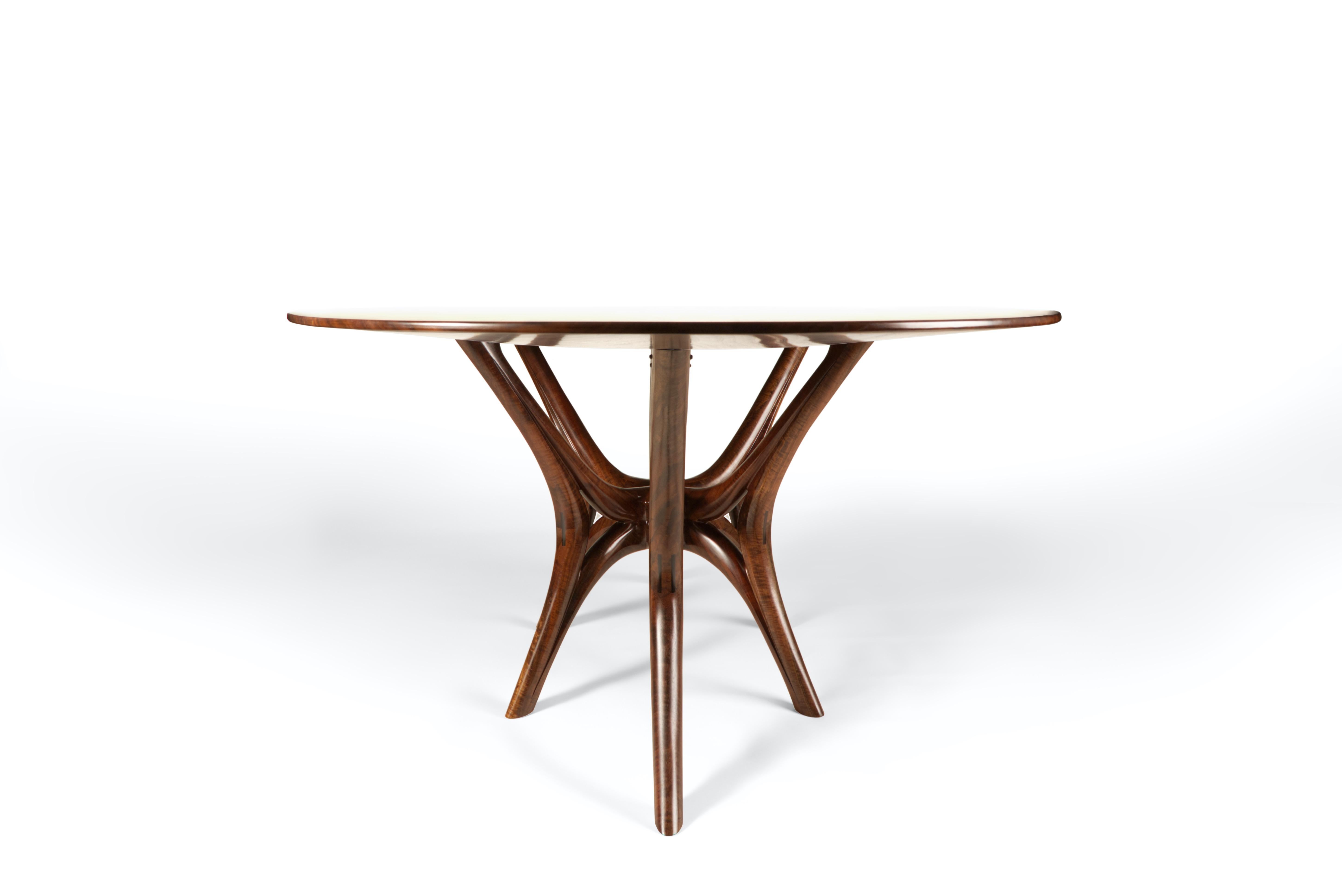 Handcrafted from solid Walnut, this web-leg dining table is a statement in Craft and design. It's hand carved legs offer an incredible sense of movement and the tapered profile of the table top makes it appear to almost be floating in space. This