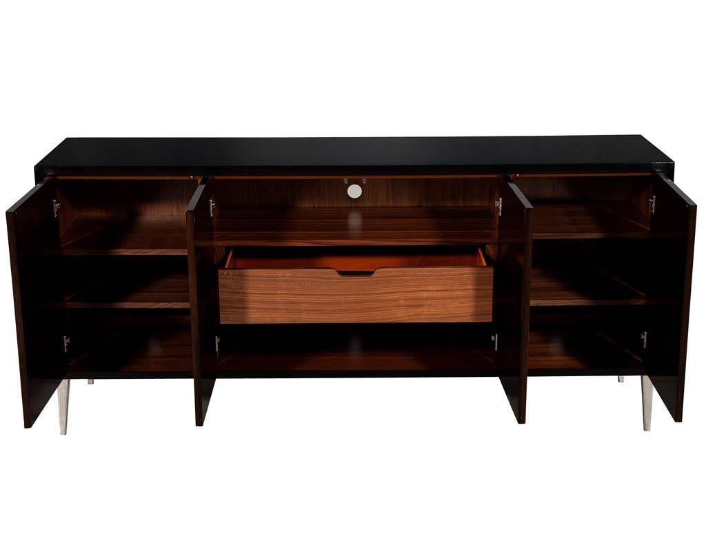 Modern walnut sunburst sideboard buffet credenza. Featuring stunning hand polished black lacquer finish with dark walnut sunburst fronts. Completed with sleek polished stainless-steel feet. Interior has ample storage options with 4 adjustable