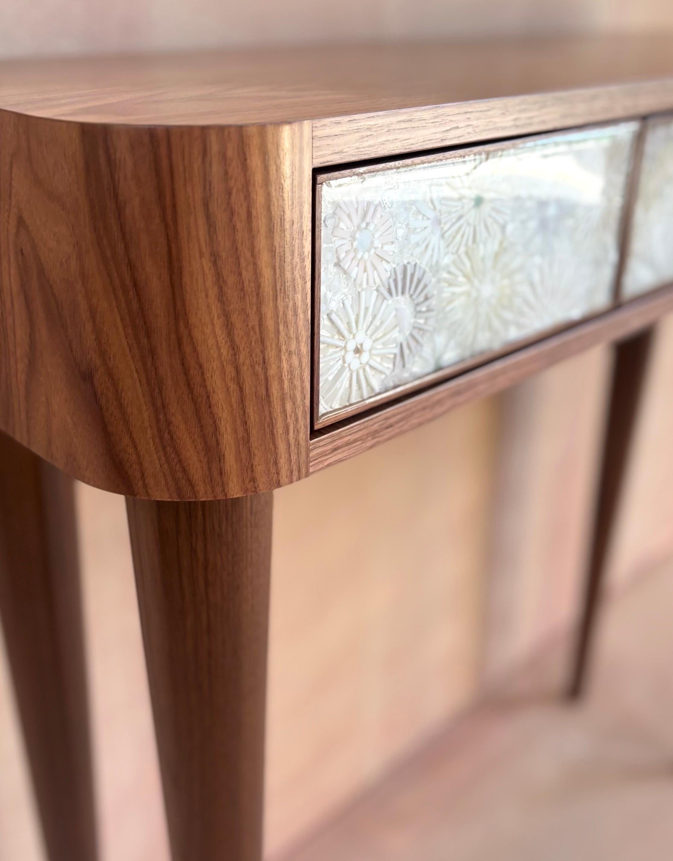 The Modern Walnut Three Drawer Wildflower Mosaic with Resin Vanity Console by Ercole Home features elegant tapered Walnut Legs, in a Natural Finish. Three drawers with hand-cut glass Wildflower Mosaic, covered in Resin. Touch-latch drawers. 

Custom