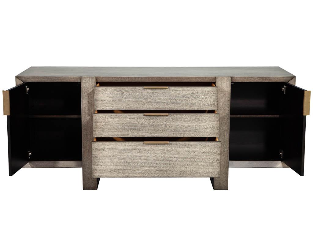 Modern washed finished sideboard Barbara Barry horizon buffet. Beautiful sleek design with a washed distressed modern finish. Featuring 3 large pull out drawers with 2 doors including adjustable shelves. Completed with sleek metal brass plated