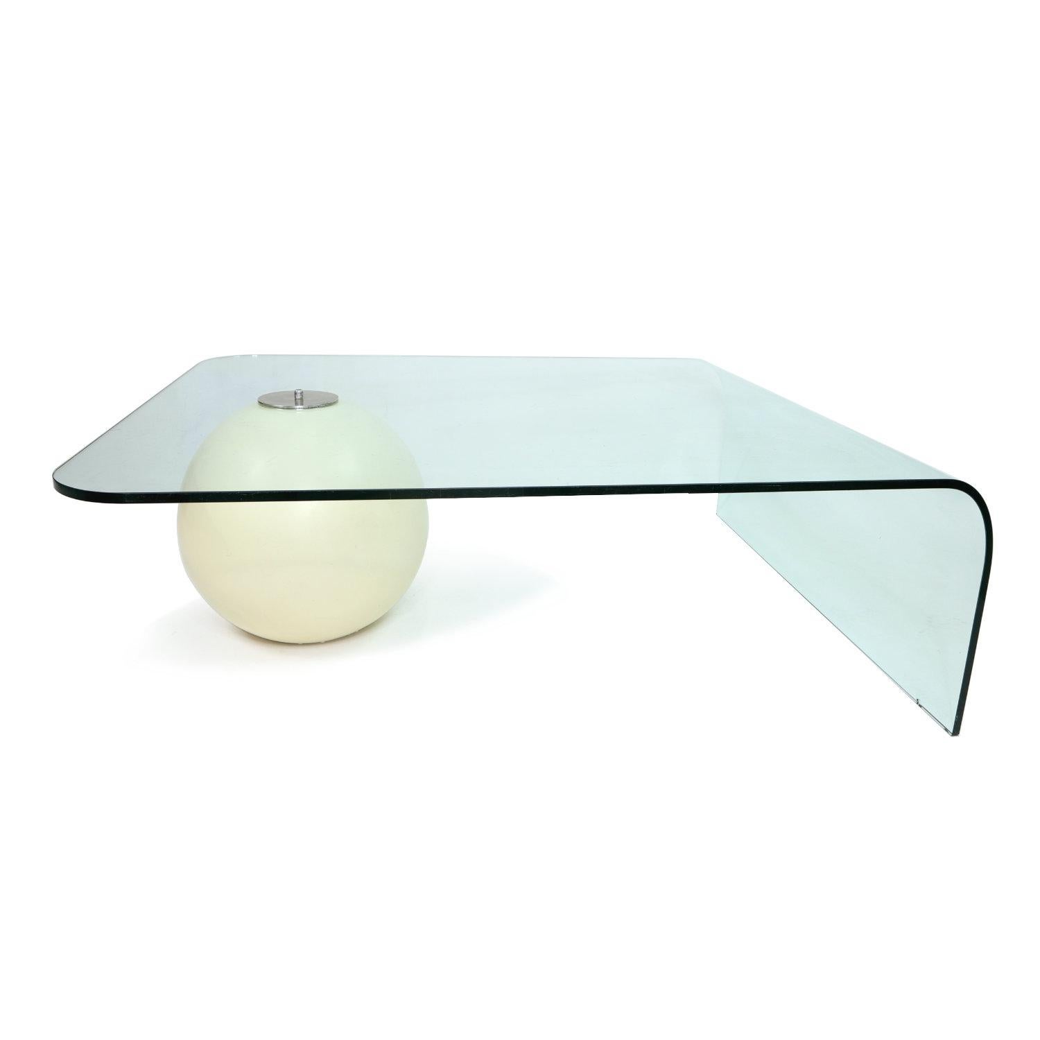 The curved glass coffee table is a functional work of art. The graceful, contoured single glass pane balances on a white ball. The white enamel paint is original, several decades old. It is no longer pure white, but rather a warm “antiqued” white.