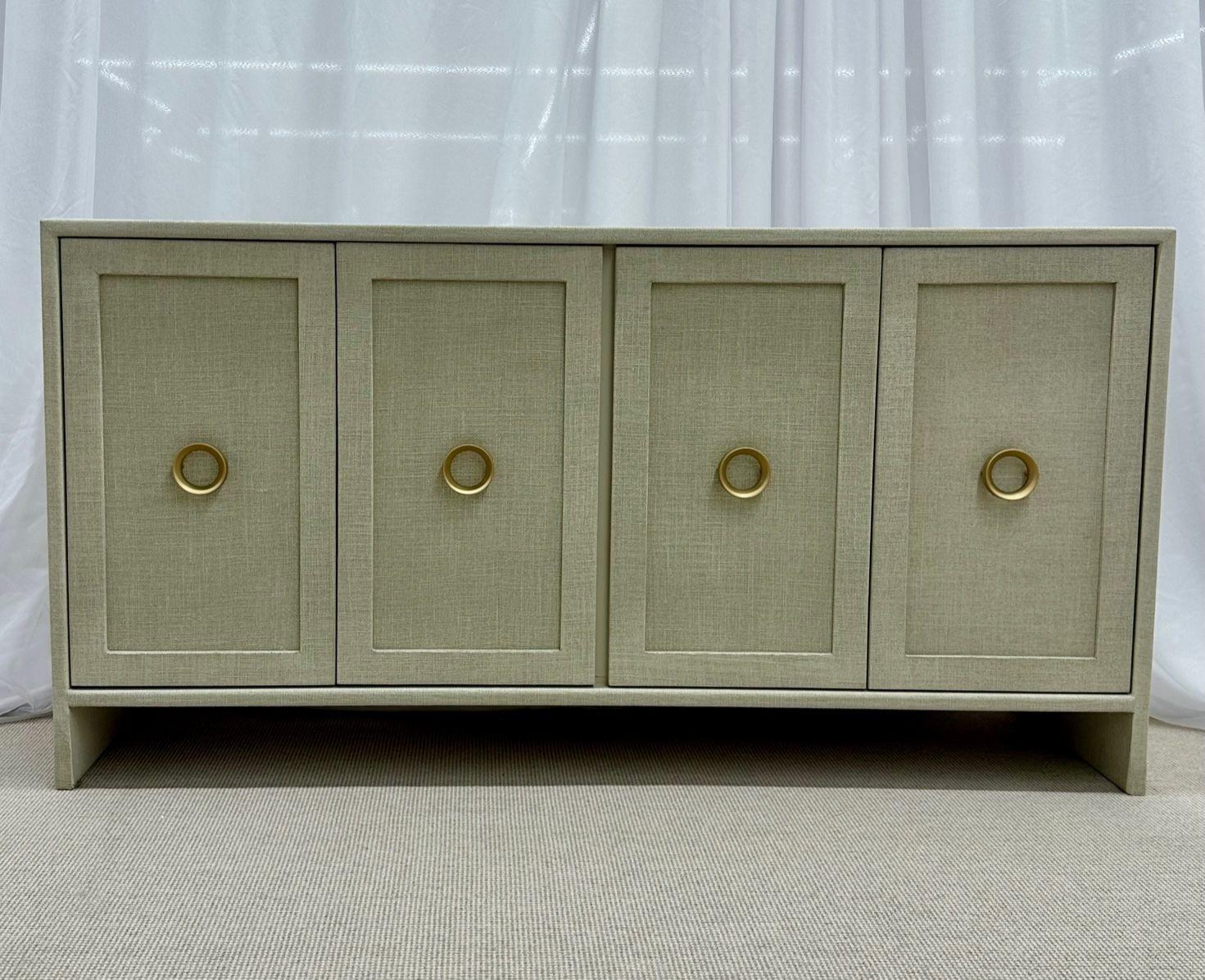 Modern white custom four door linen wrapped sideboard / credenza, brass
Contemporary decorative cabinet hand wrapped in linen and given a multi-layered paint glaze in a neutral oyster color. Having two pairs of double doors that open to shelving;