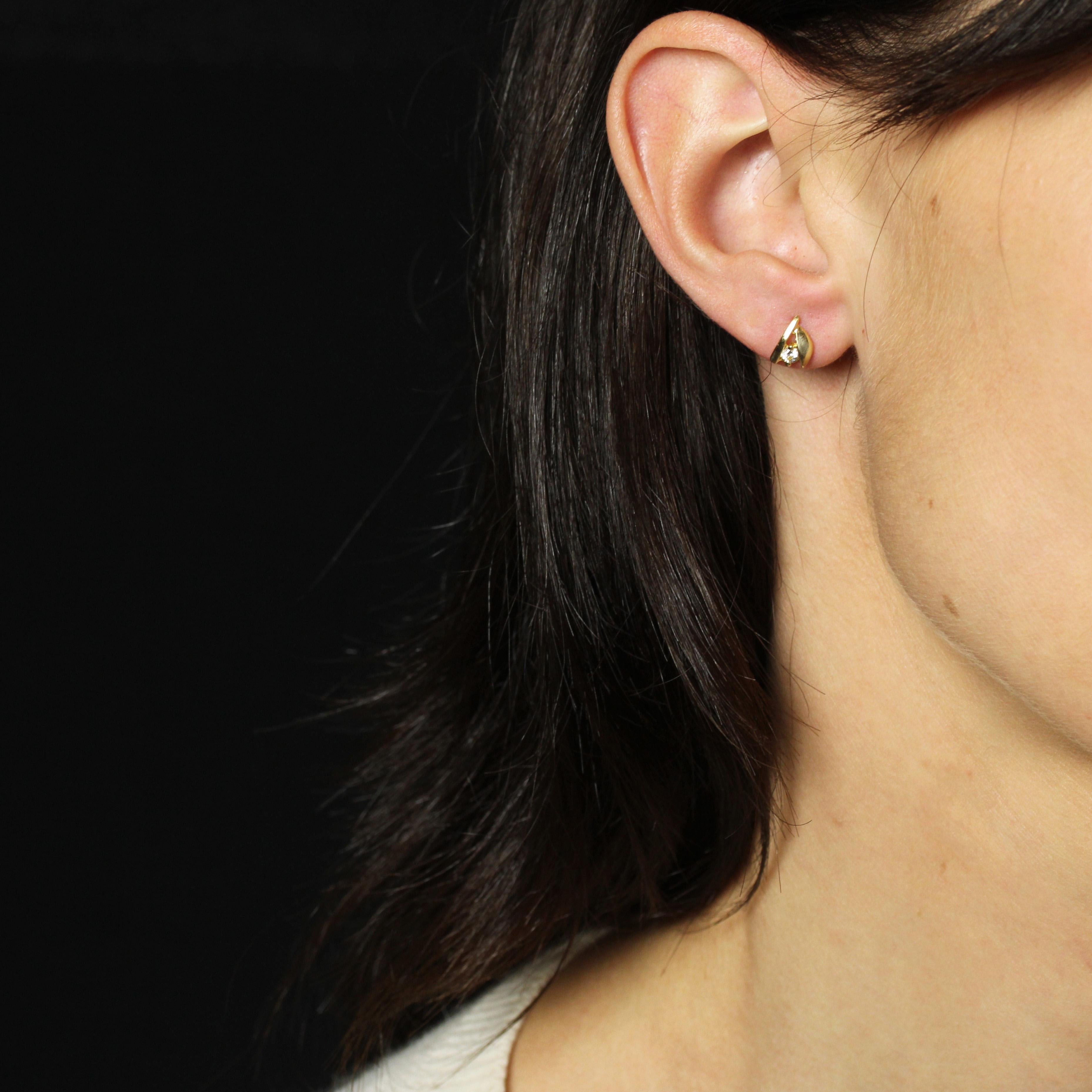 Pour les oreilles percées.
Boucles d'oreilles en or jaune 18 carats.
Chaque boucle d'oreille est ornée d'une pierre blanche retenue par 2 griffes, d'un motif linéaire de part et d'autre et d'un motif demi-lune légèrement bombé en or jaune. Le