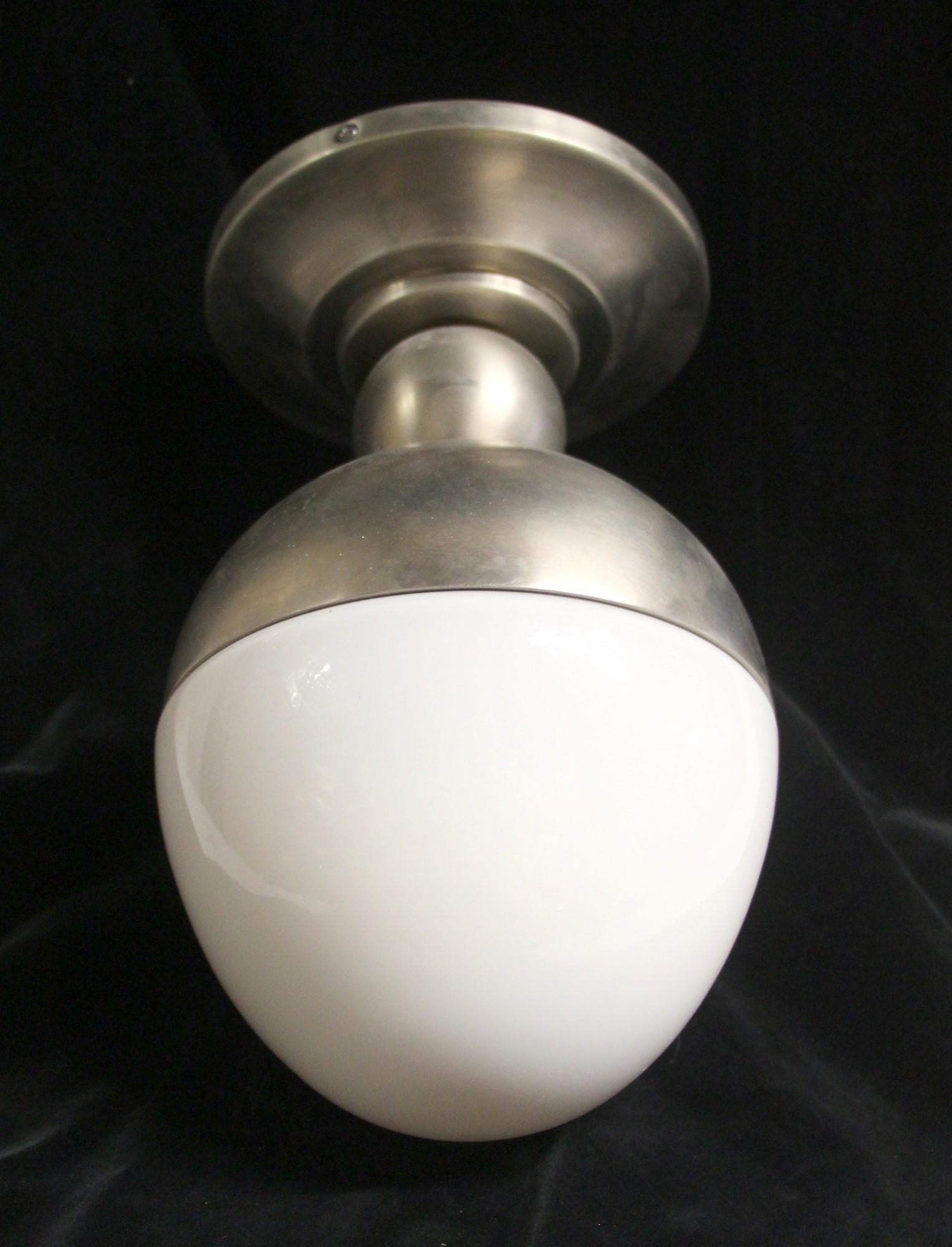 Modern style white milk glass egg light with a satin nickel finish and steel base. This can be seen at our 302 Bowery location in NoHo in Manhattan.