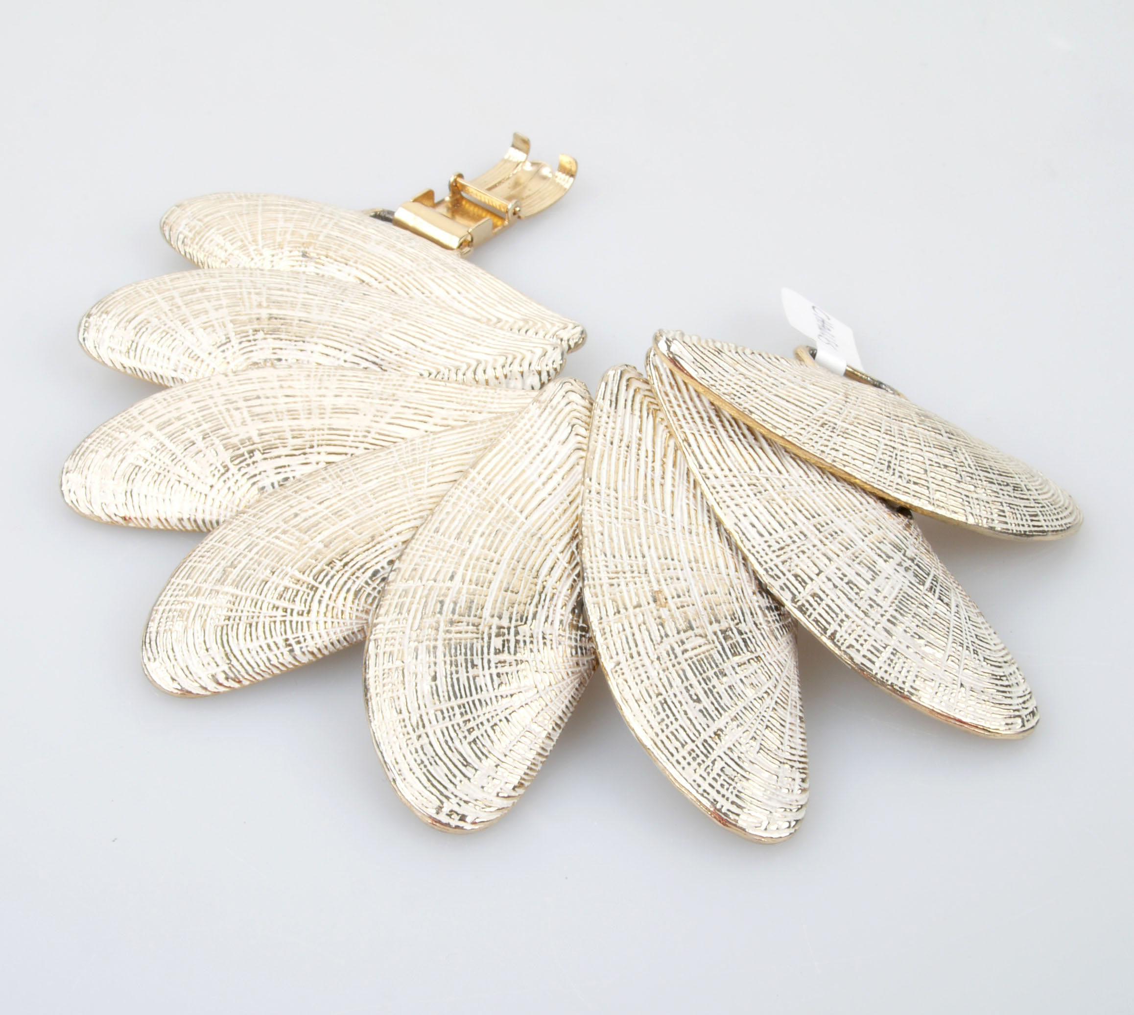 White and gold tone seashell bracelet with fold-over clasp closure.