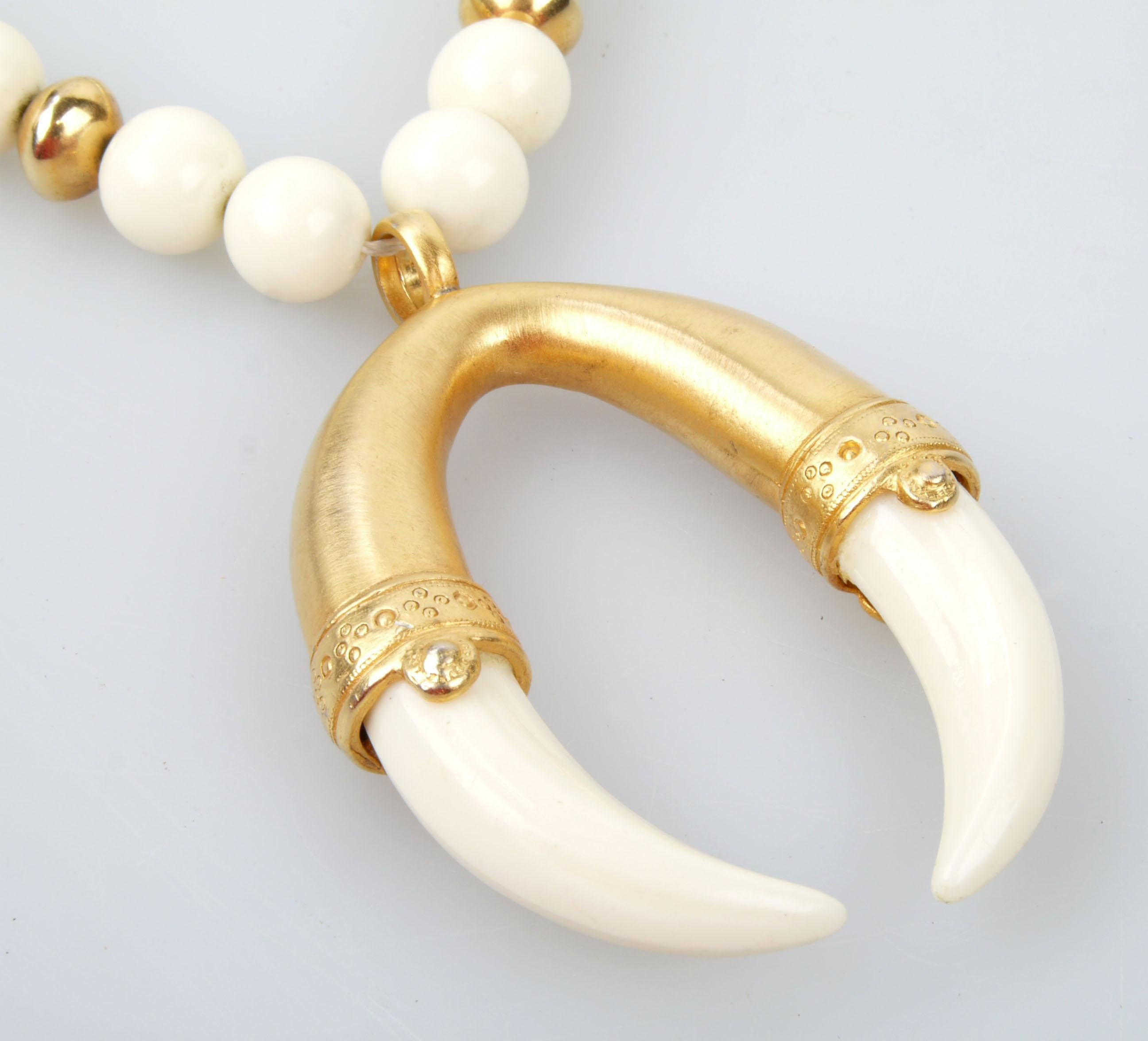 Modern white and gold-tone faux-pearl necklace with large tusk pendant. 
Faux-pearls made of glass-filled resin.

 