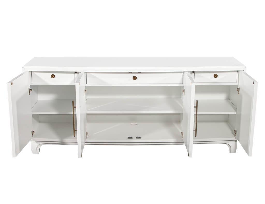 Modern white lacquered sideboard cabinet with reeded doors. Art Deco and Danish Modern influenced sideboard with reeded doors and a contoured front. Cabinet has 3 inside drawers and adjustable shelves finished in a designer white satin lacquer.